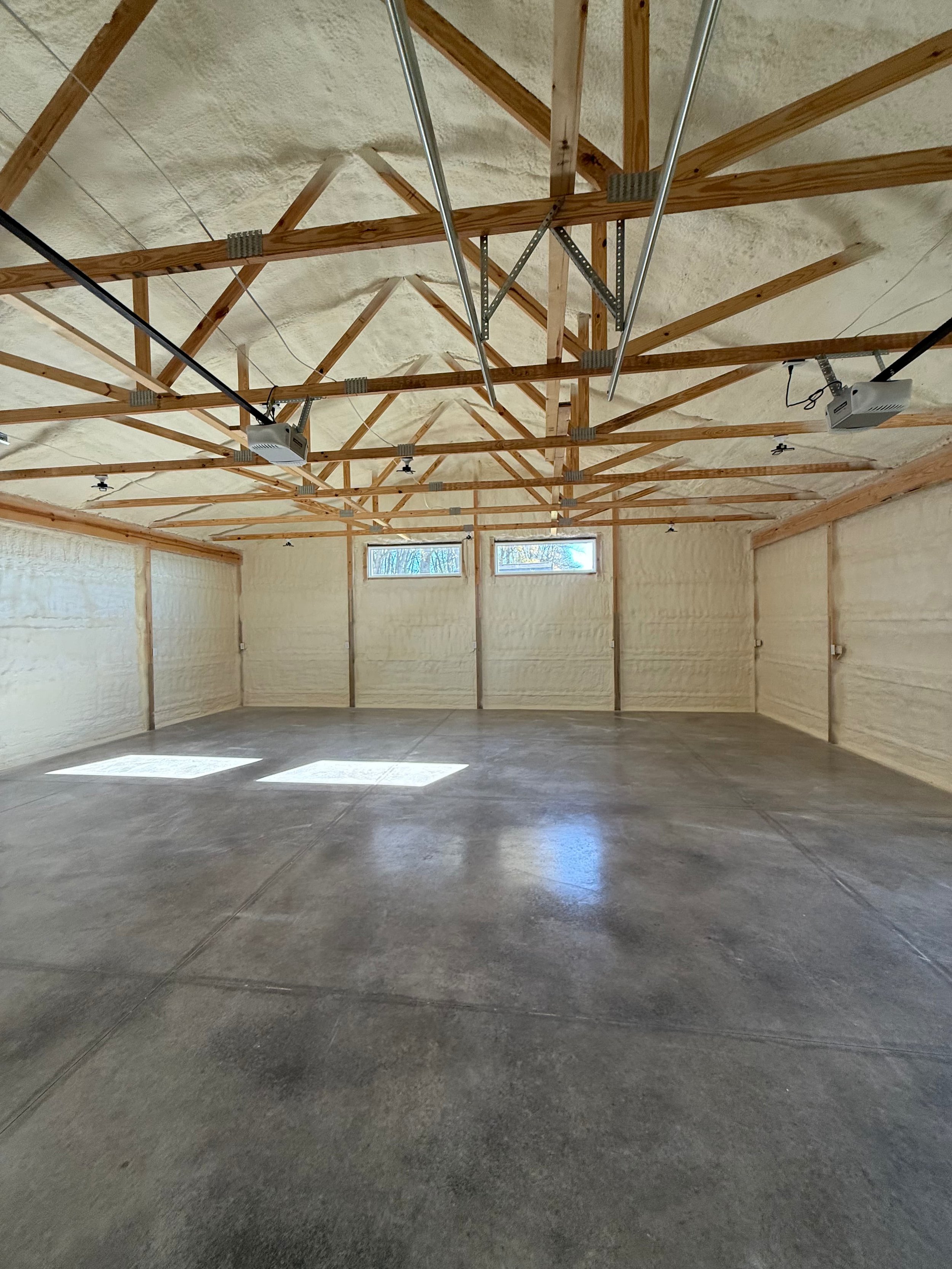 spray foam insulation on roof trusses and interior walls of a three-car garage with overhead doors — Summit Sprayfoam, central Ohio
