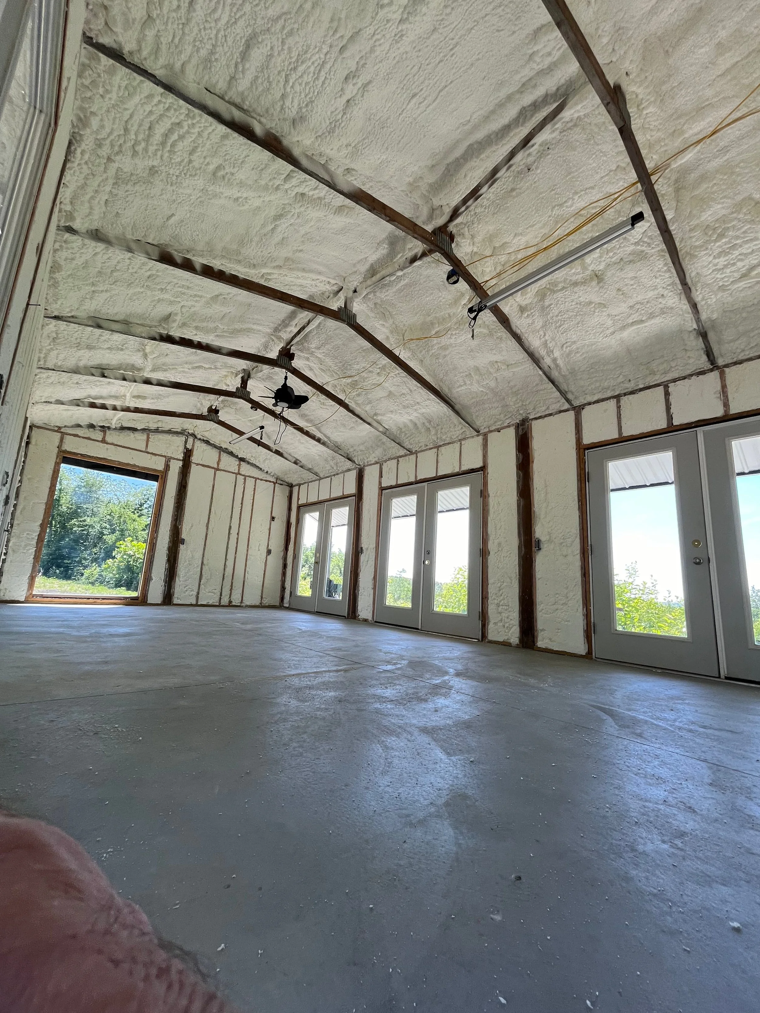 spray foam insulation applied to interior walls of a residential garage workshop with window and equipment — Summit Sprayfoam, Ohio