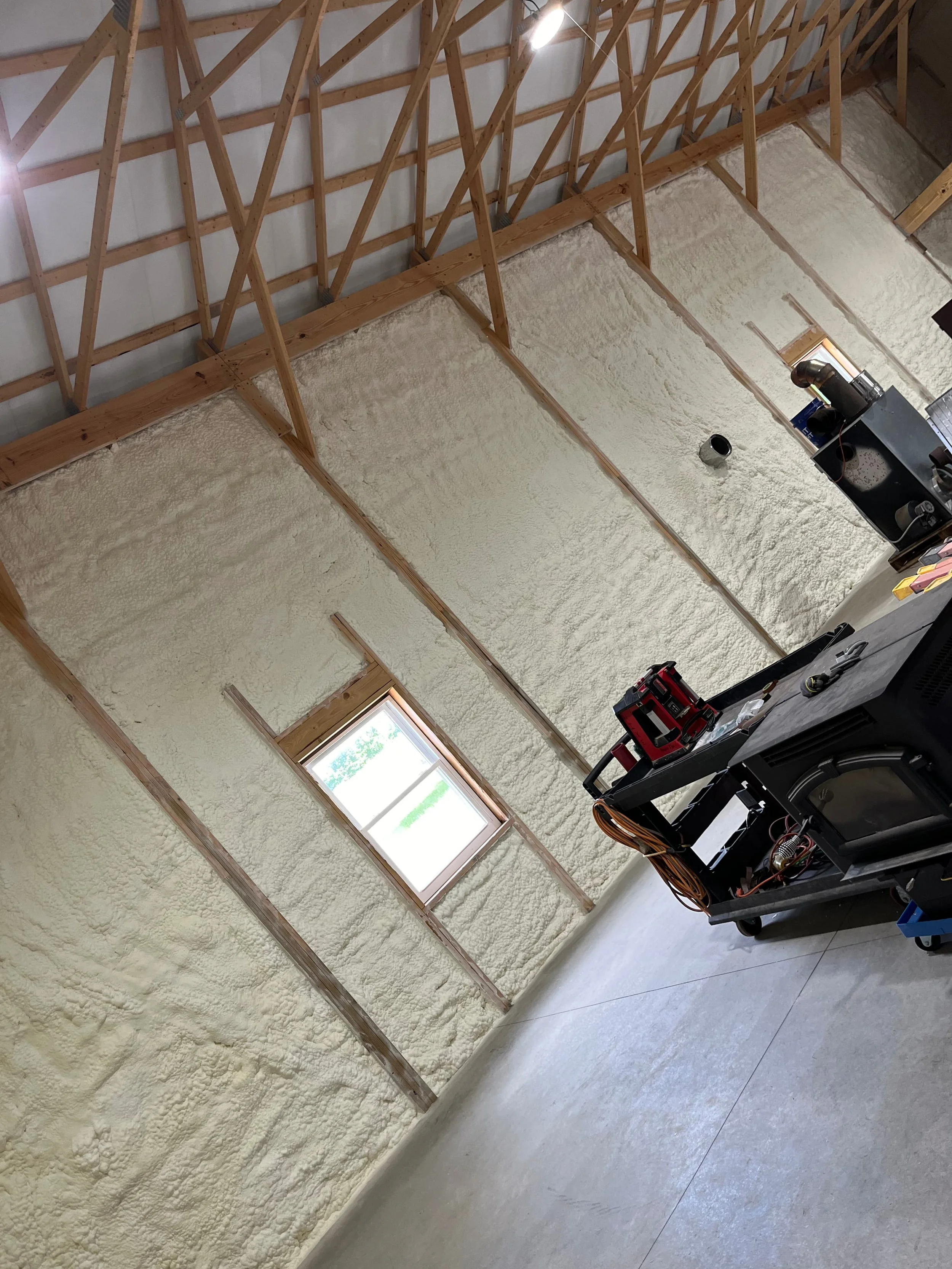 spray foam insulation applied to interior walls of a residential garage workshop with window and equipment — Summit Sprayfoam, Ohio