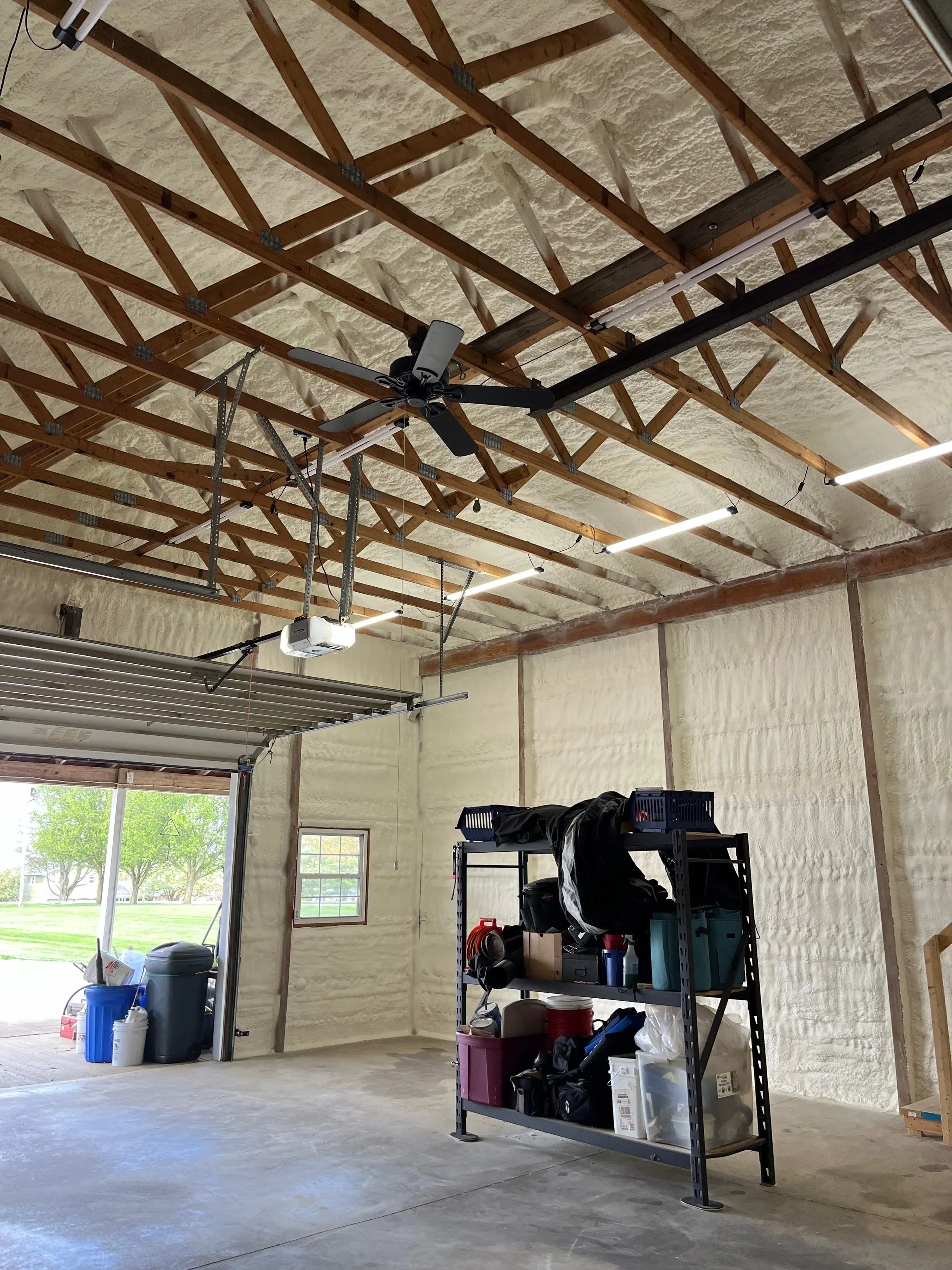 completed spray foam insulation on roof trusses and walls of a residential garage with overhead door and ceiling fan — Summit Sprayfoam, central Ohio