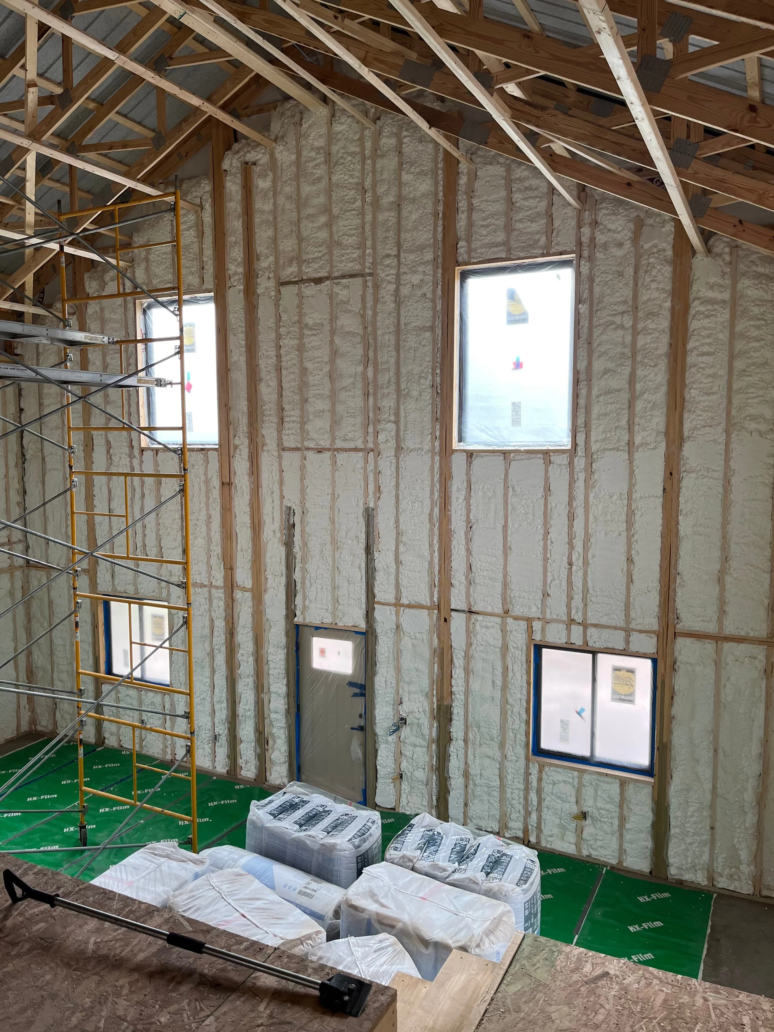 spray foam insulation applied to tall interior walls of a new construction home with scaffolding — Summit Sprayfoam, central Ohio