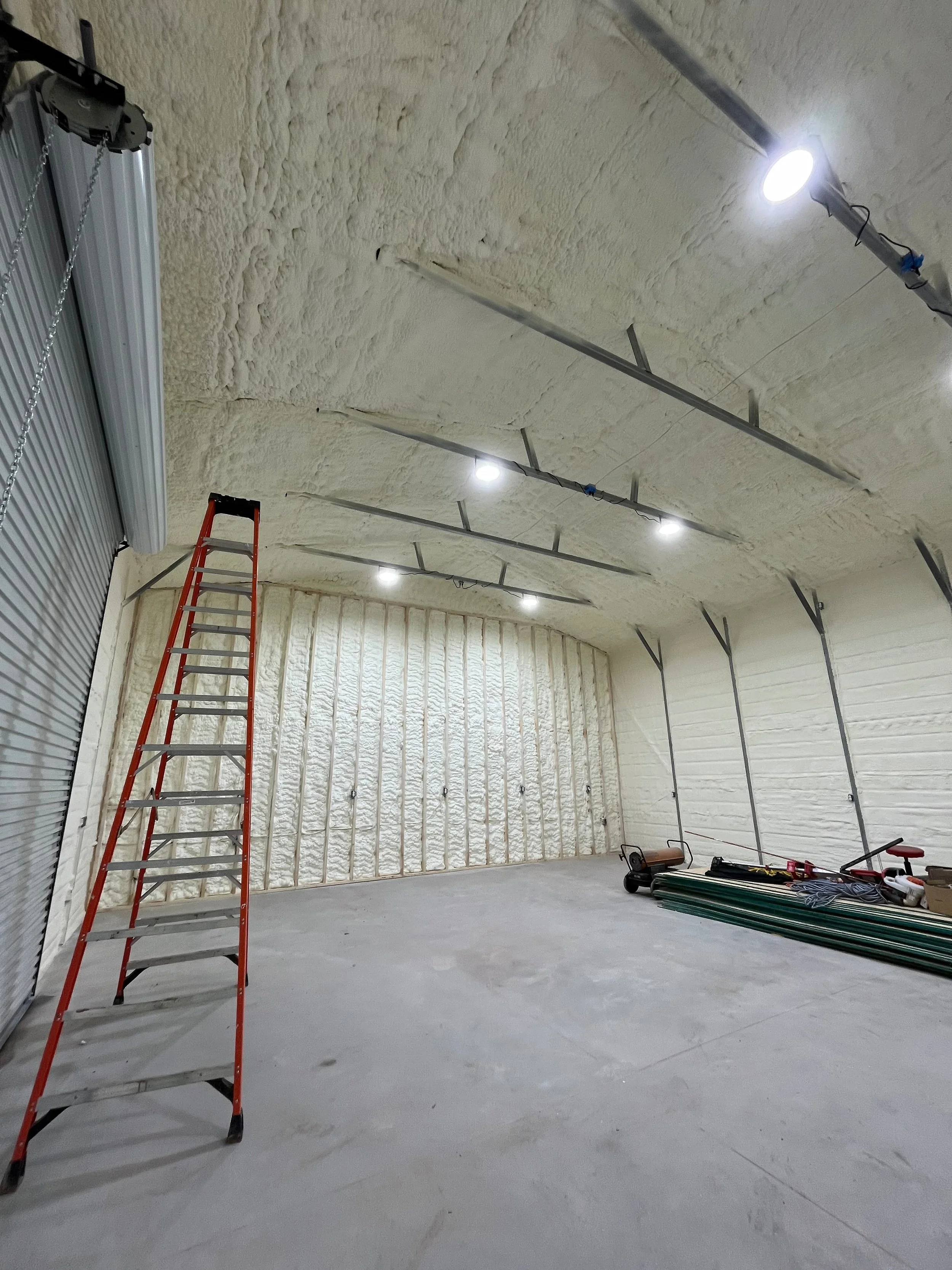 spray foam insulation on walls and ceiling of a metal commercial building with staircase and overhead lighting — Summit Sprayfoam, Ohio