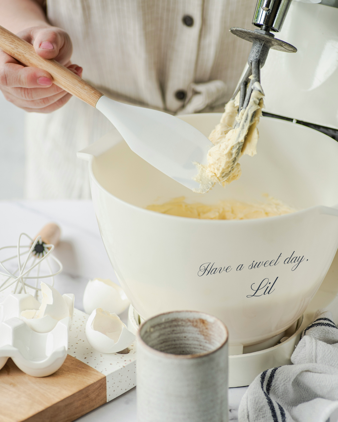 Woman baking batter with the words "Have a sweet day, Lil" on the mixing bowl