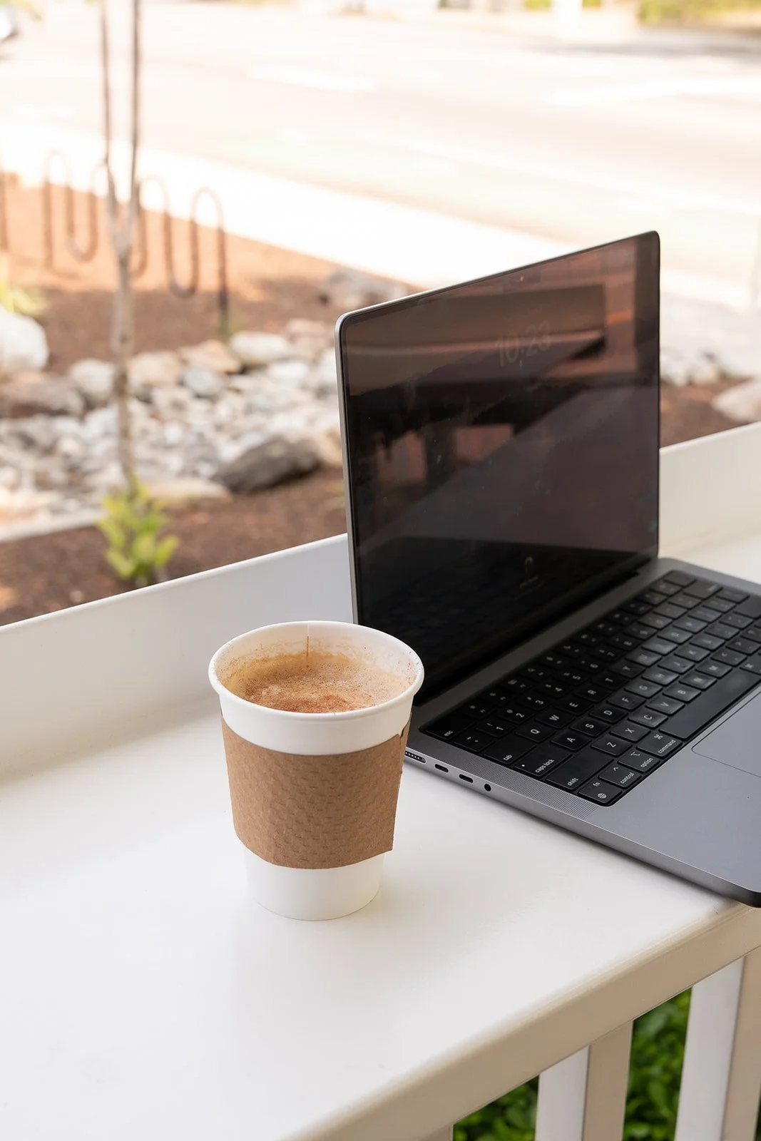 Open laptop and latte sitting on table outside