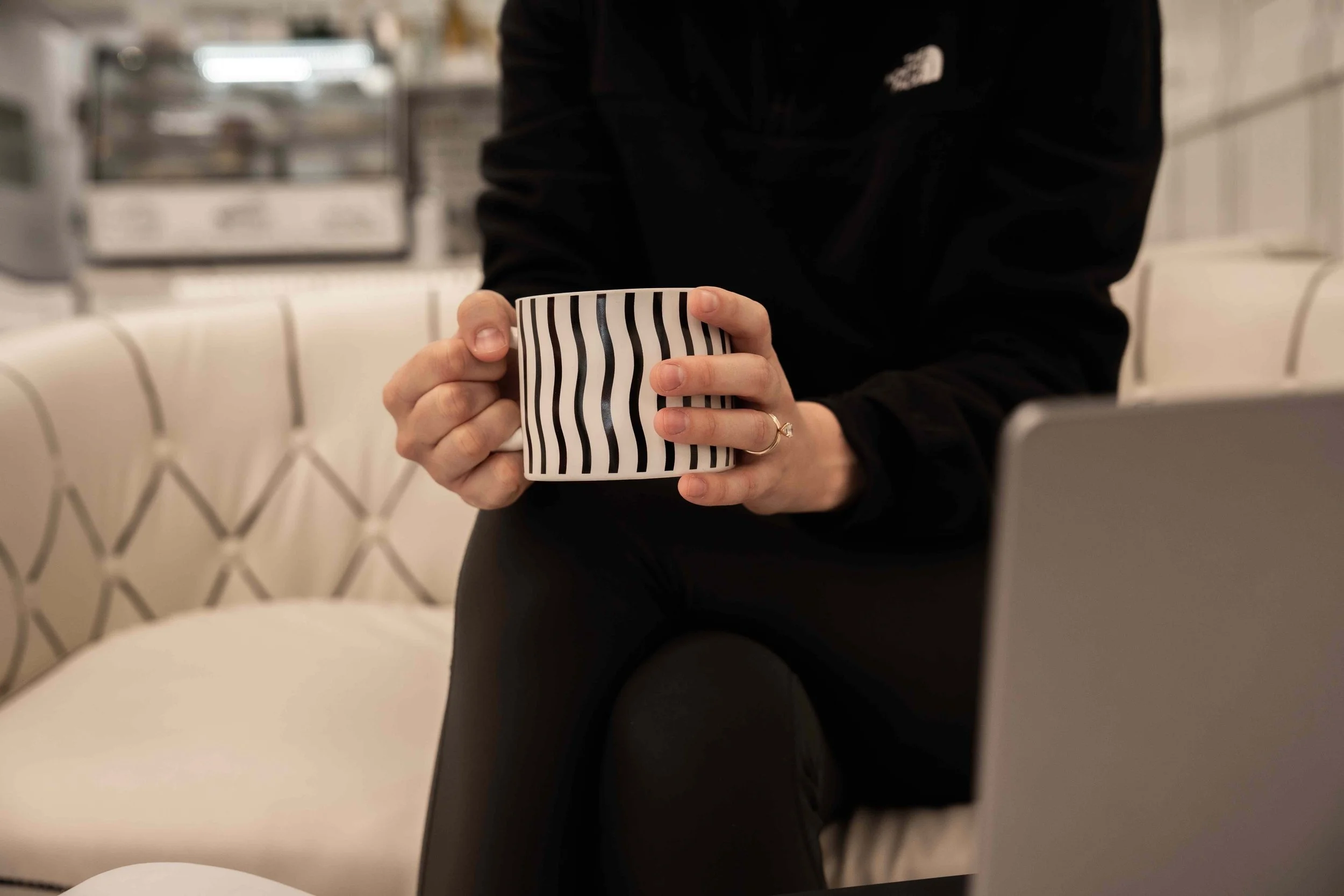 Woman sipping coffee at 2D Cafe sitting on white couch