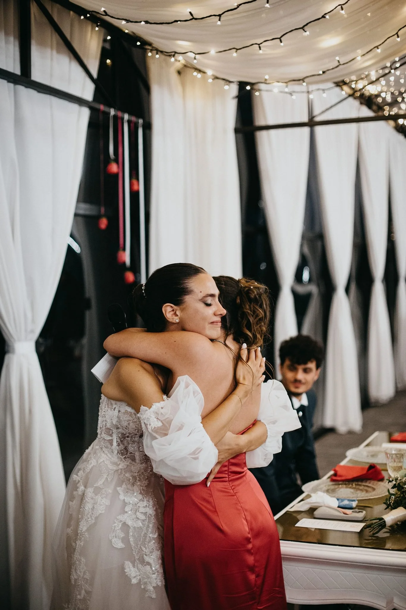 La sposa abbraccia commossa la damigella durante un discorso a cena
