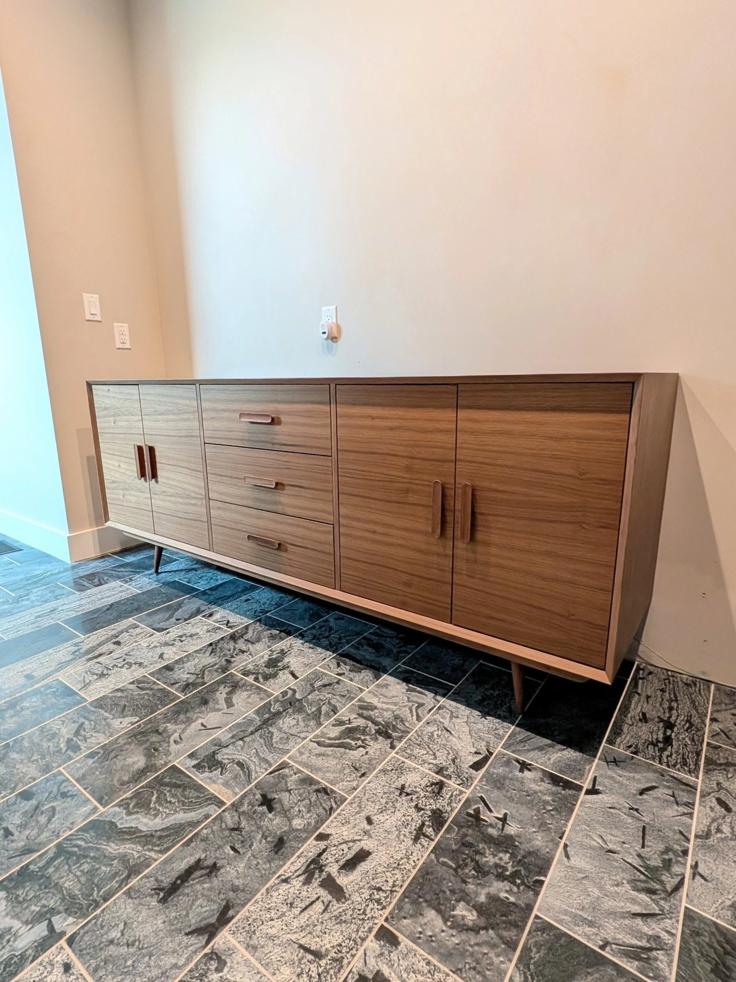 Mid century modern vanity in walnut.

This custom vanity featured grain-matched walnut doors and drawer fronts, walnut interior, a chamfered frame edge profile, and mid century style legs and pulls. 

88" L x 34.5" H x 22" D

Looking f