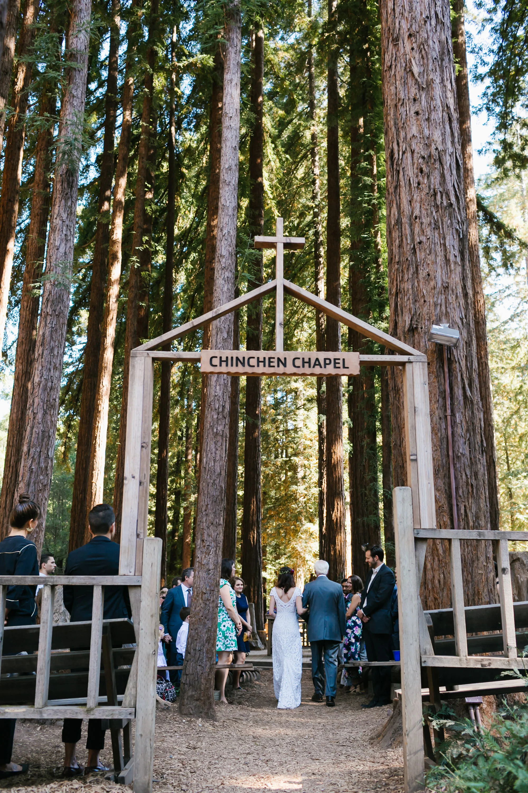 Bride and her father walk into the wedding ceremony in outdoor chapel