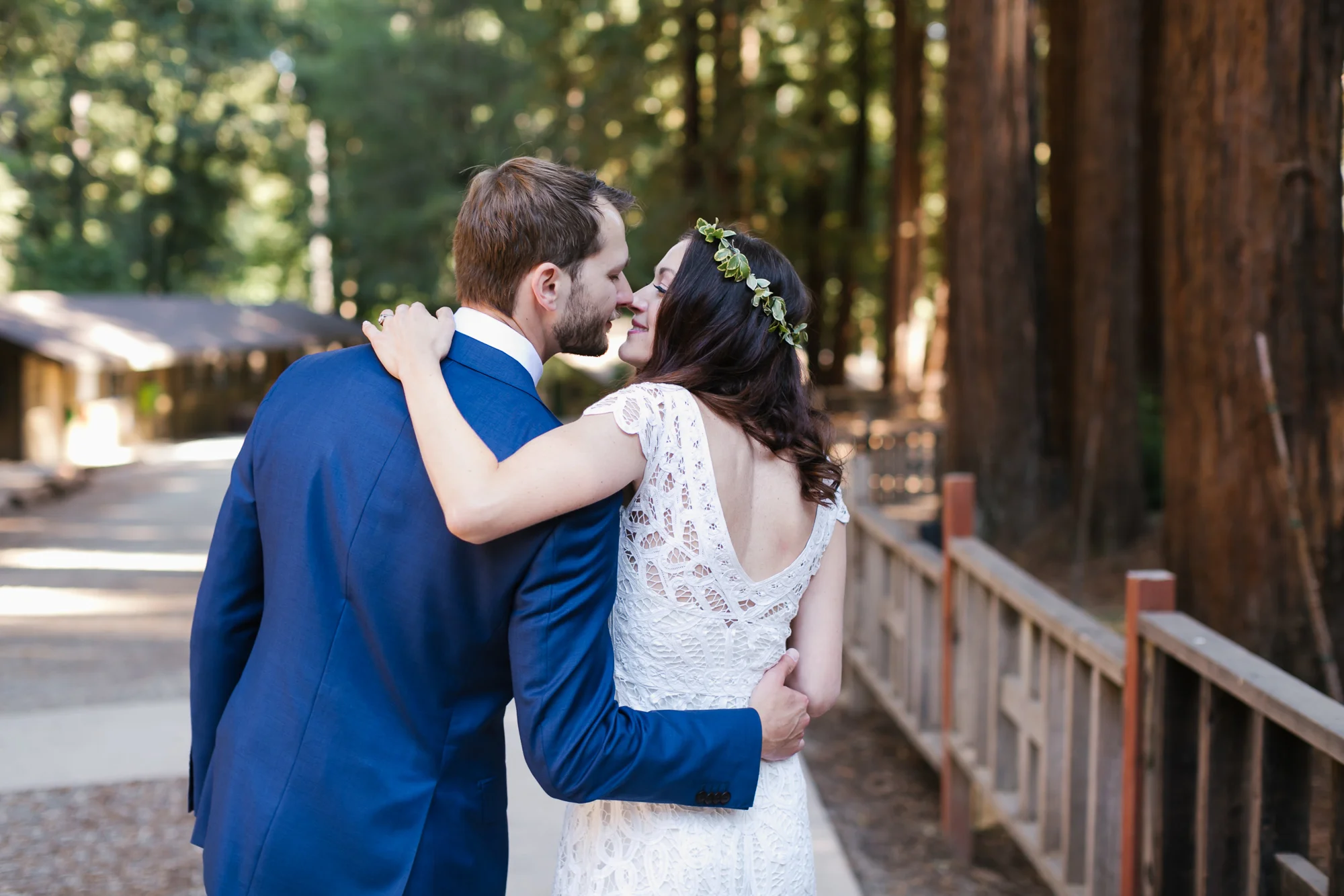 Groom in blue suit is about to kiss his bride in white lace gown