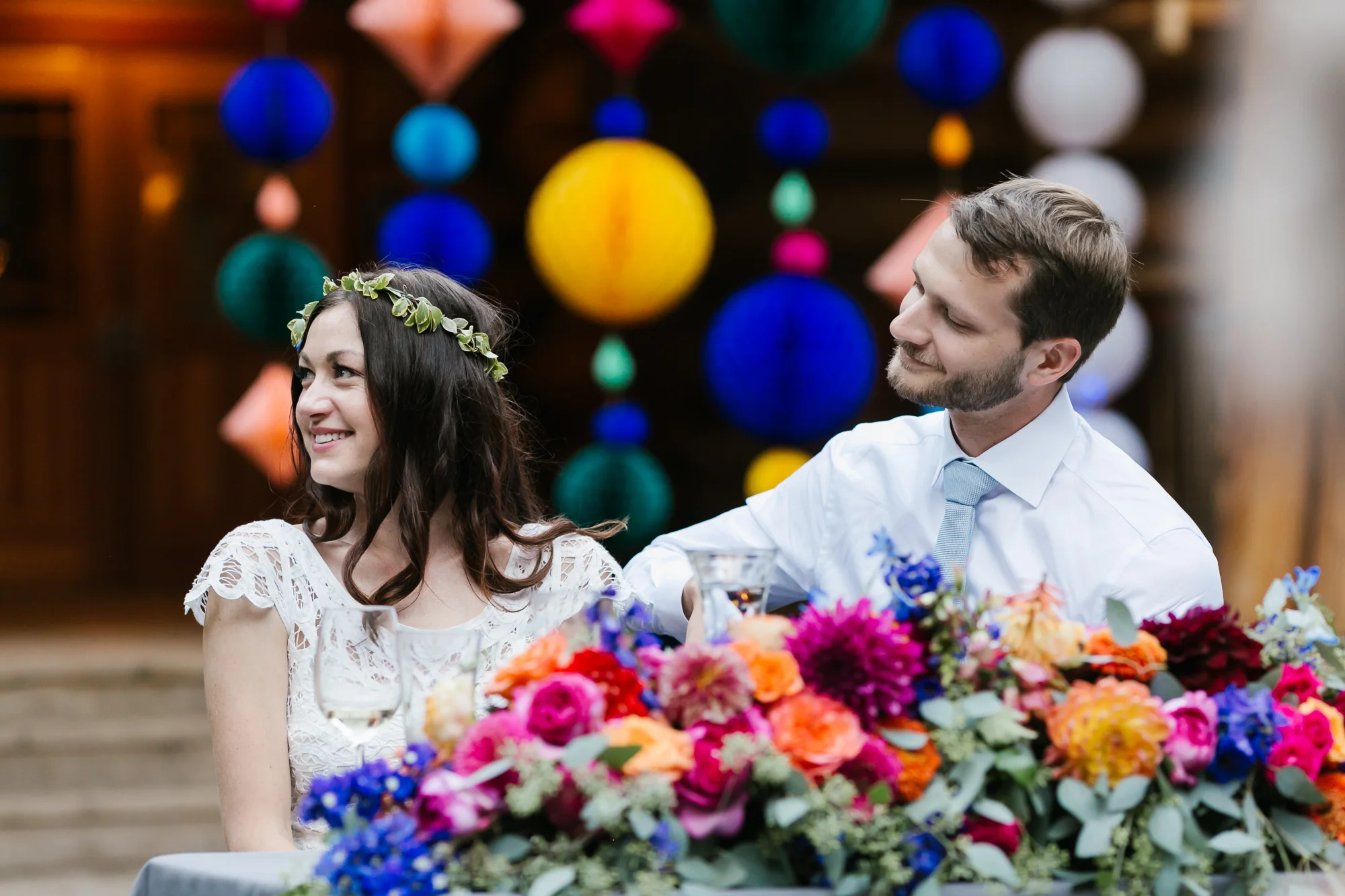 Bride and groom enjoy speeches during their colorful outdoor wedding reception