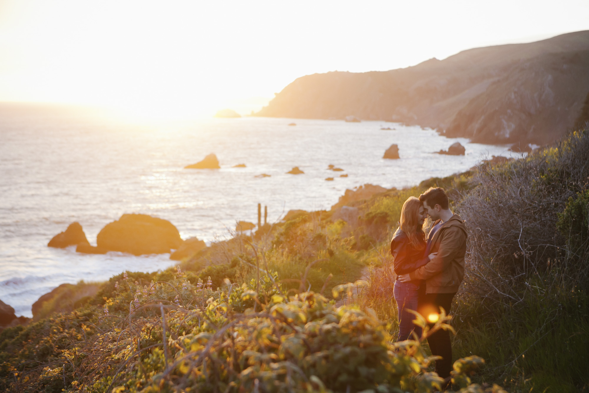 Couple embrace at sunset on the coast of Northern California at Slide Ranch