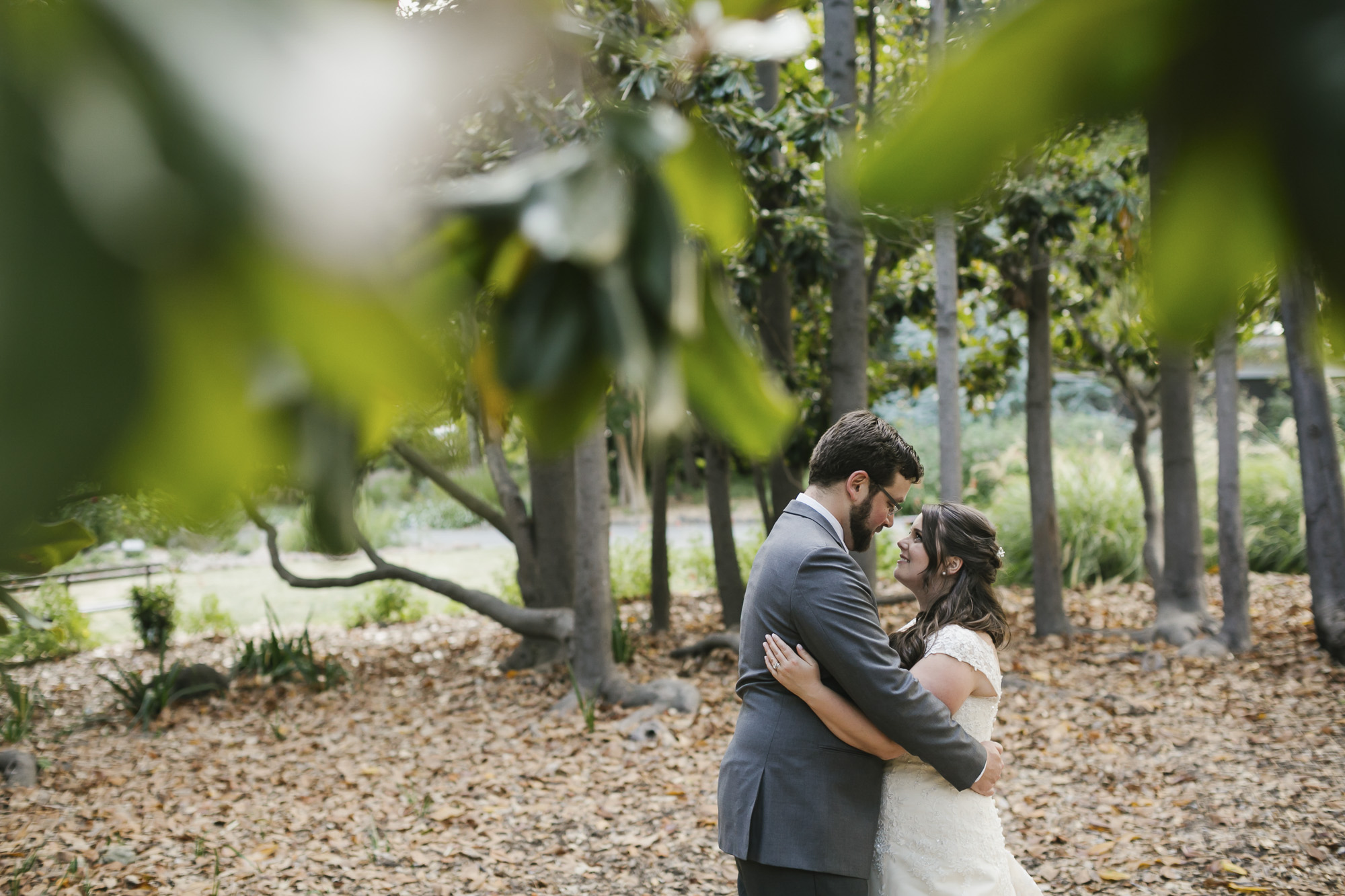 A wedding couple hug surrounded by trees at the Marin Art and Garden Center
