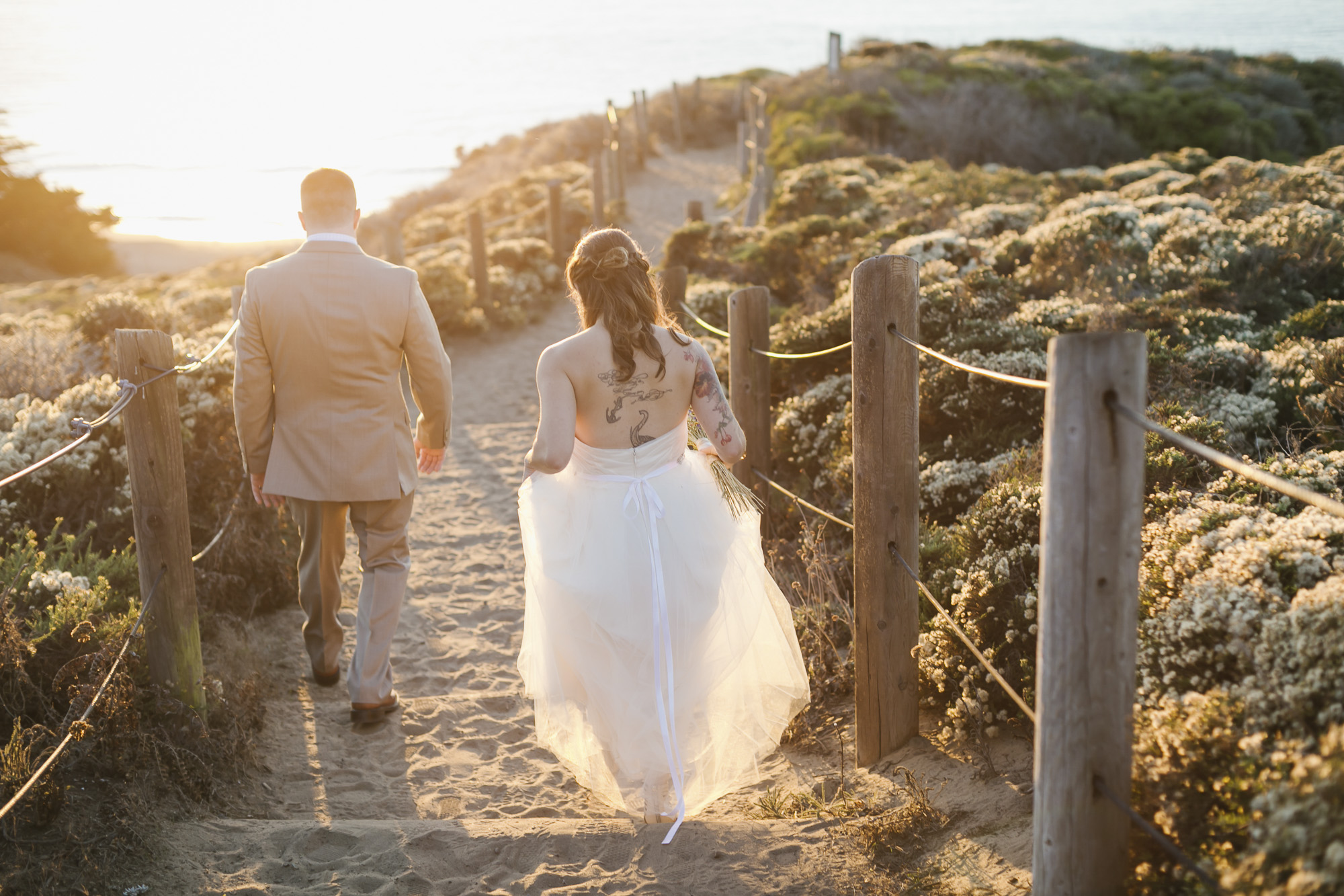 A wedding couple walk into the sunset together