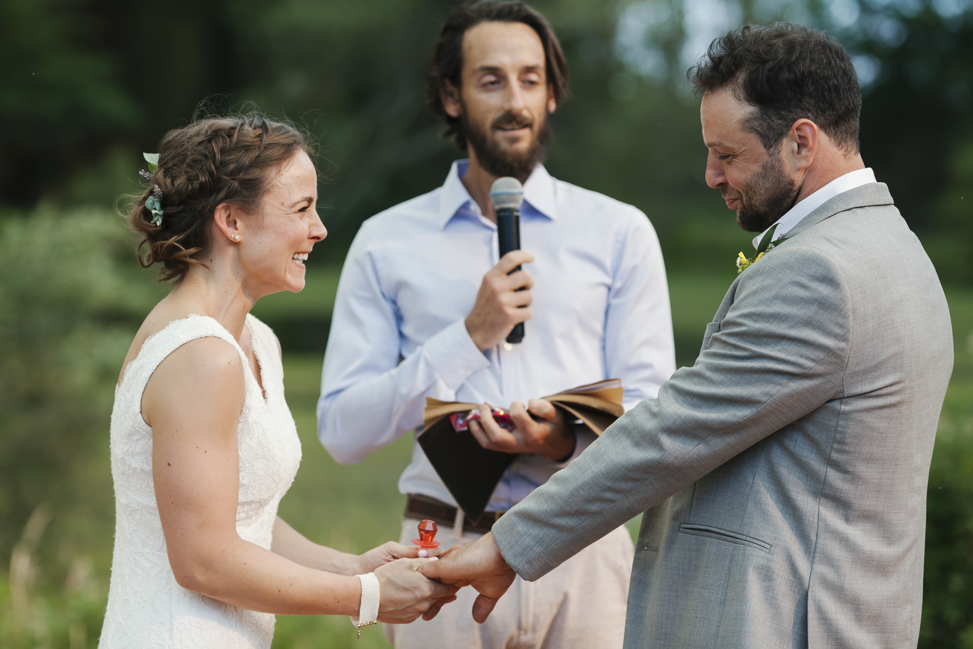 Bride wearing a red ring pop laughs as her husband makes a funny face during their wedding ceremony