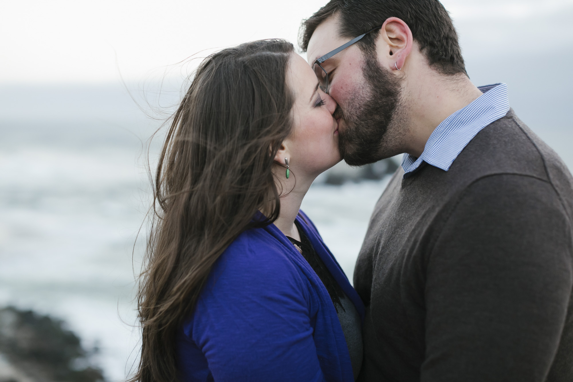 Engaged couple kiss at Lands End with ocean in the background