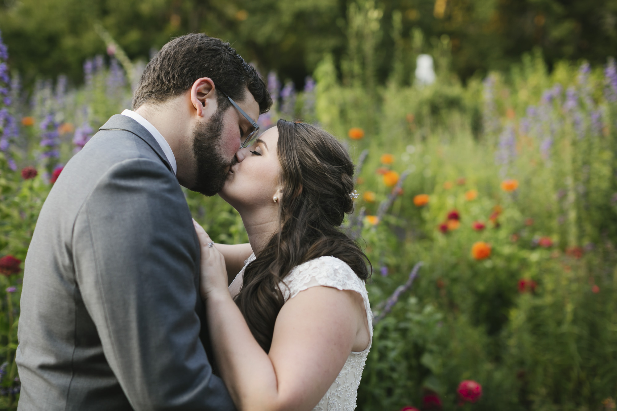 Wedding couple kiss in front of colorful flowers in Marin