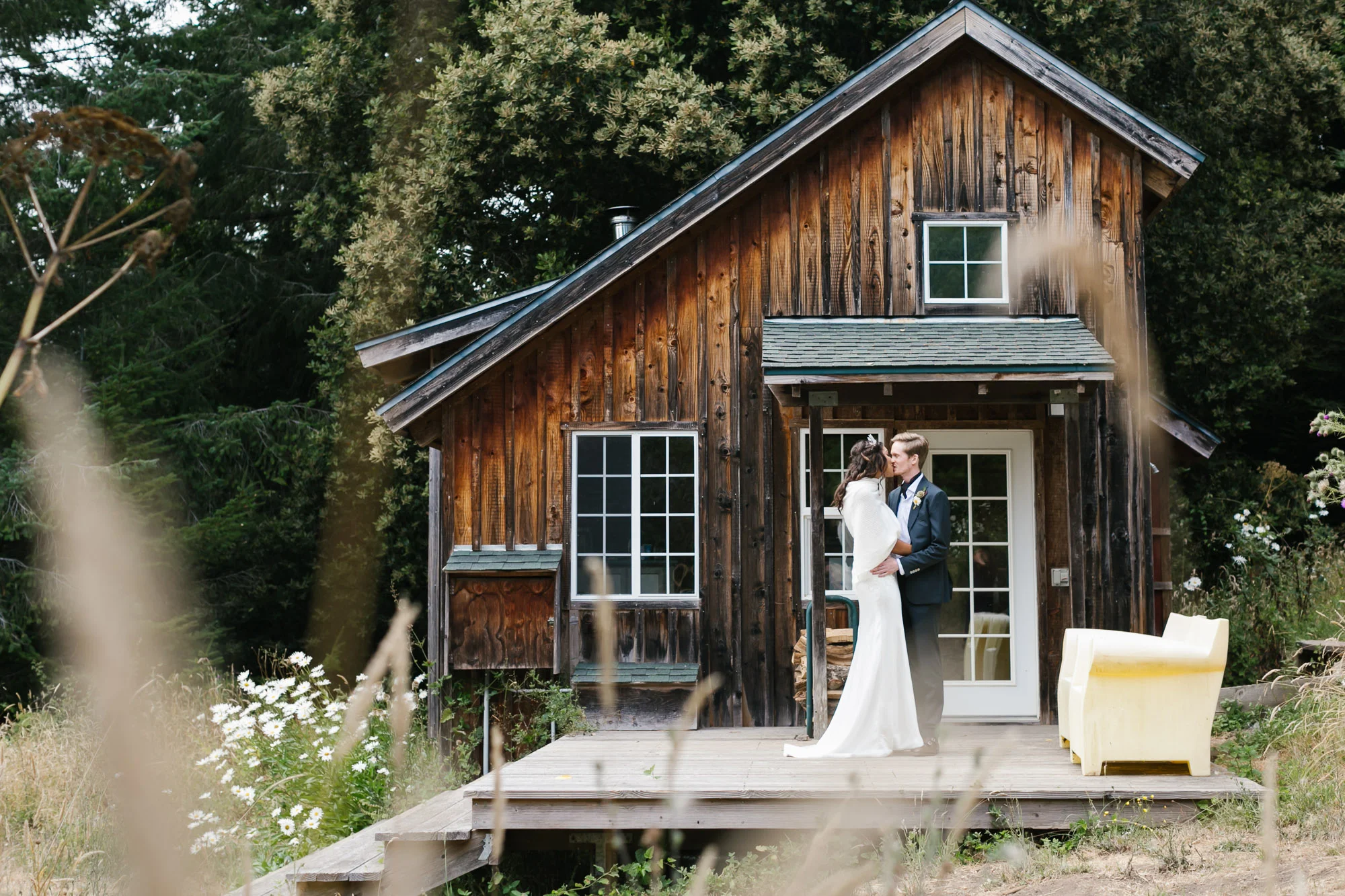Wedding couple kiss in front of charming wood cabin