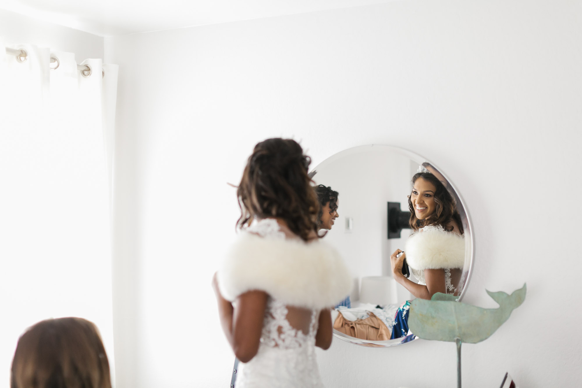 Bride smiles at her reflection in round mirror