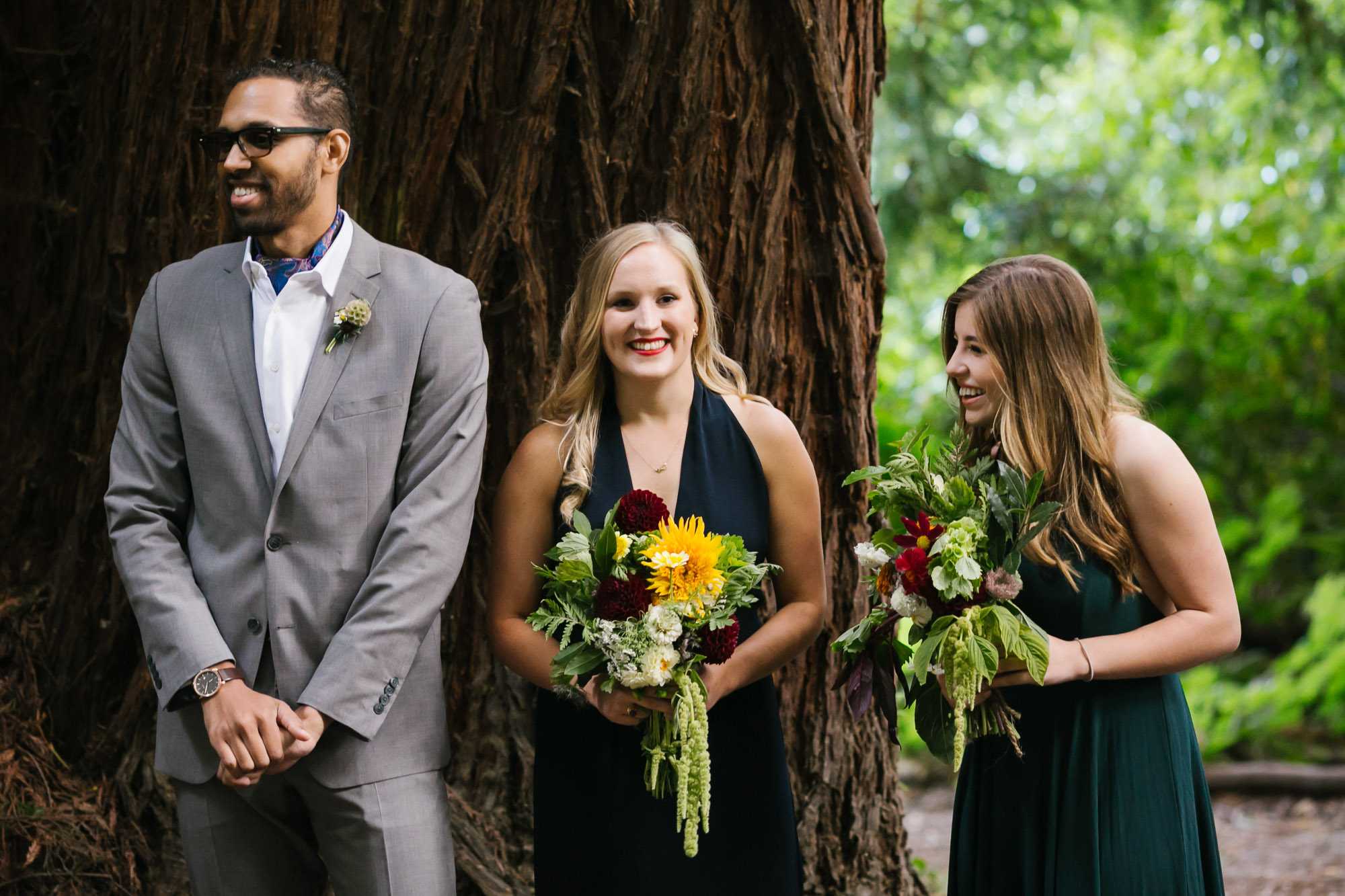 Bridesmaids laugh during wedding ceremony under the redwoods