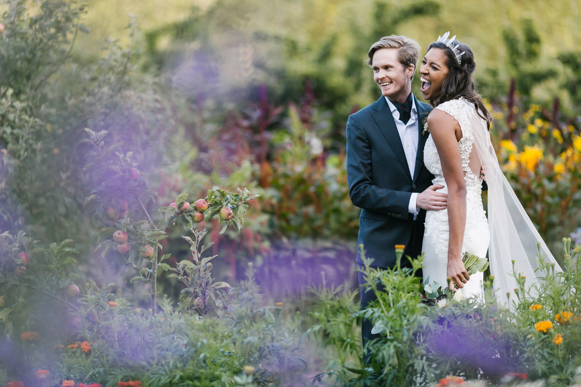 Wedding couple with flowers and apple trees at coastal farm