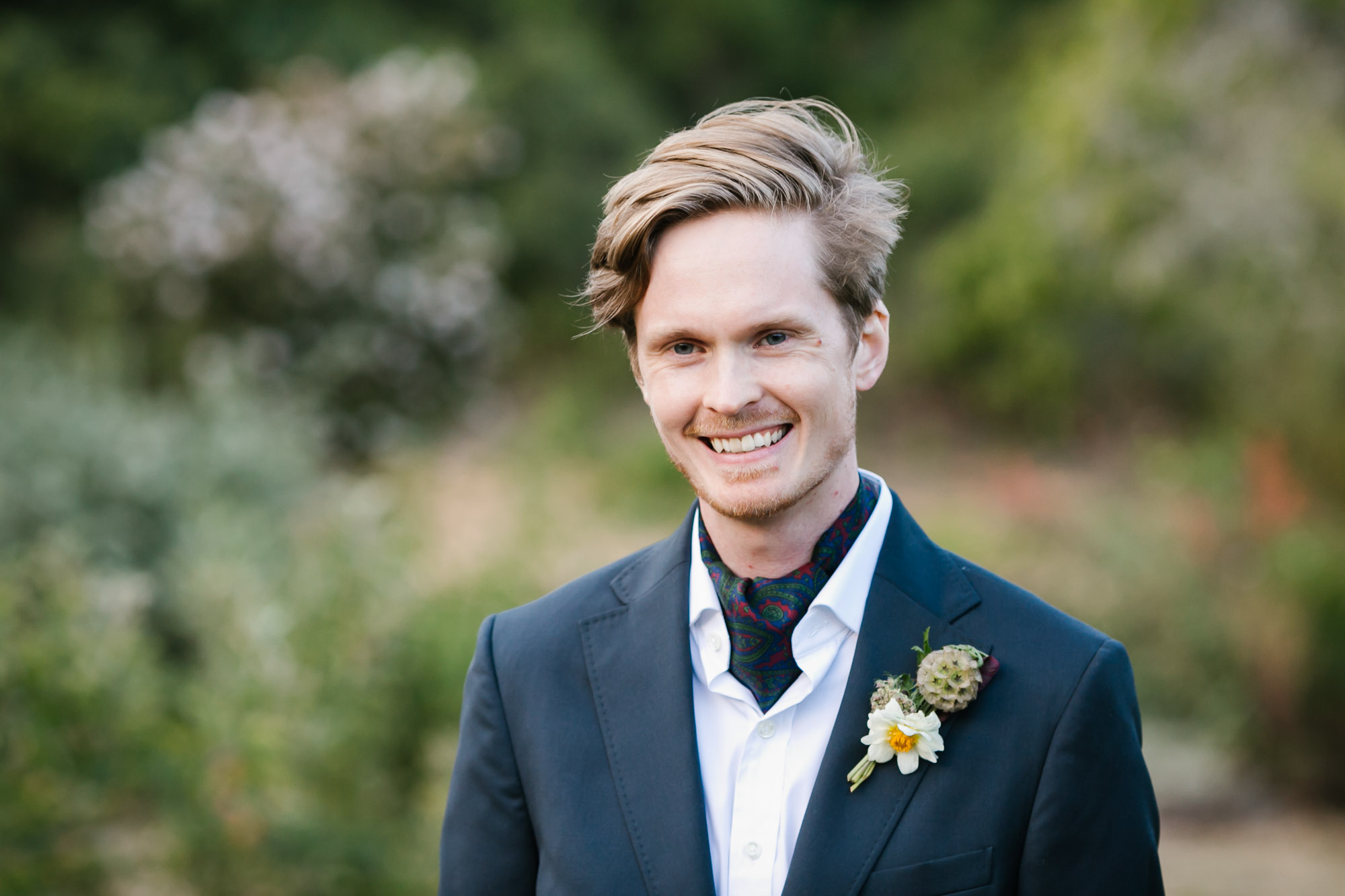 Swedish groom with blue suit and paisley ascot smiles on his wedding day
