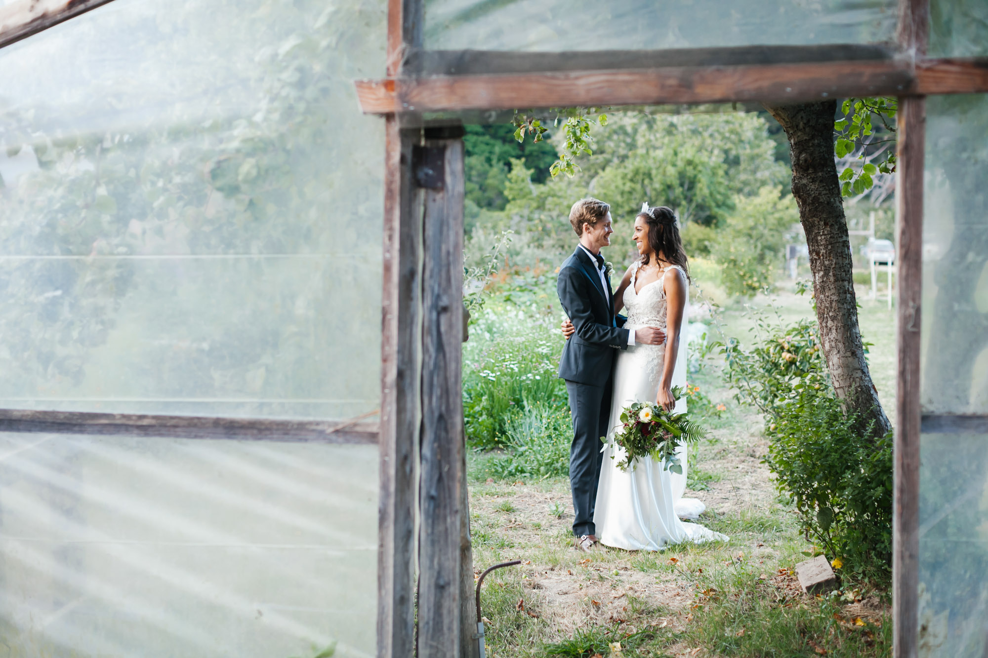 Wedding couple smile on coastal flower farm with greenhouse