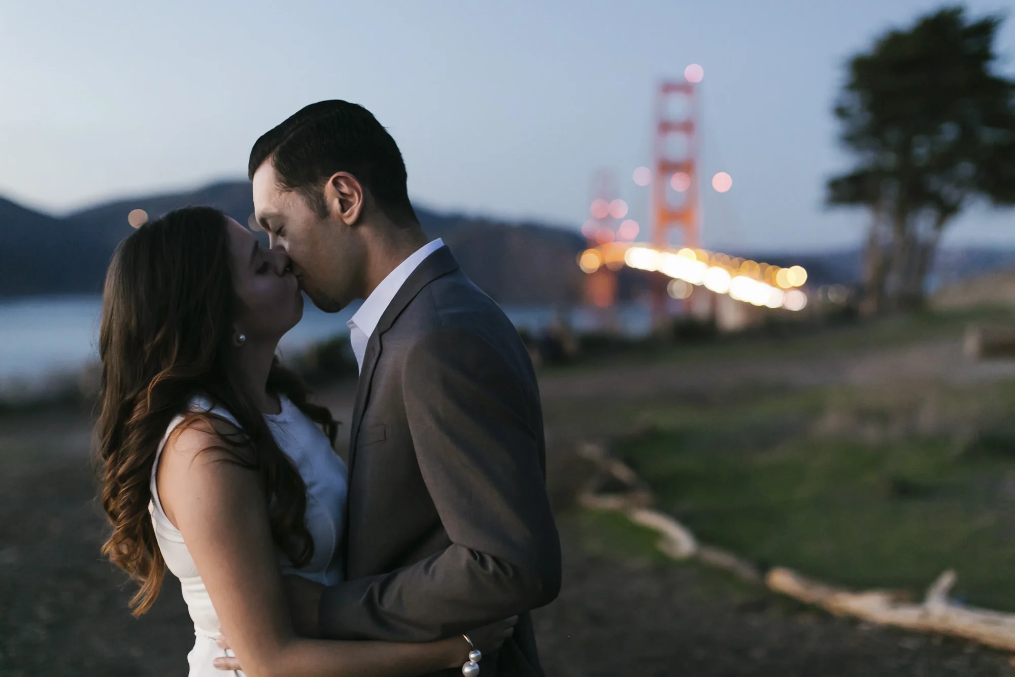 Couple kiss at dusk in front of the Golden Gate Bridge during their engagement portraits