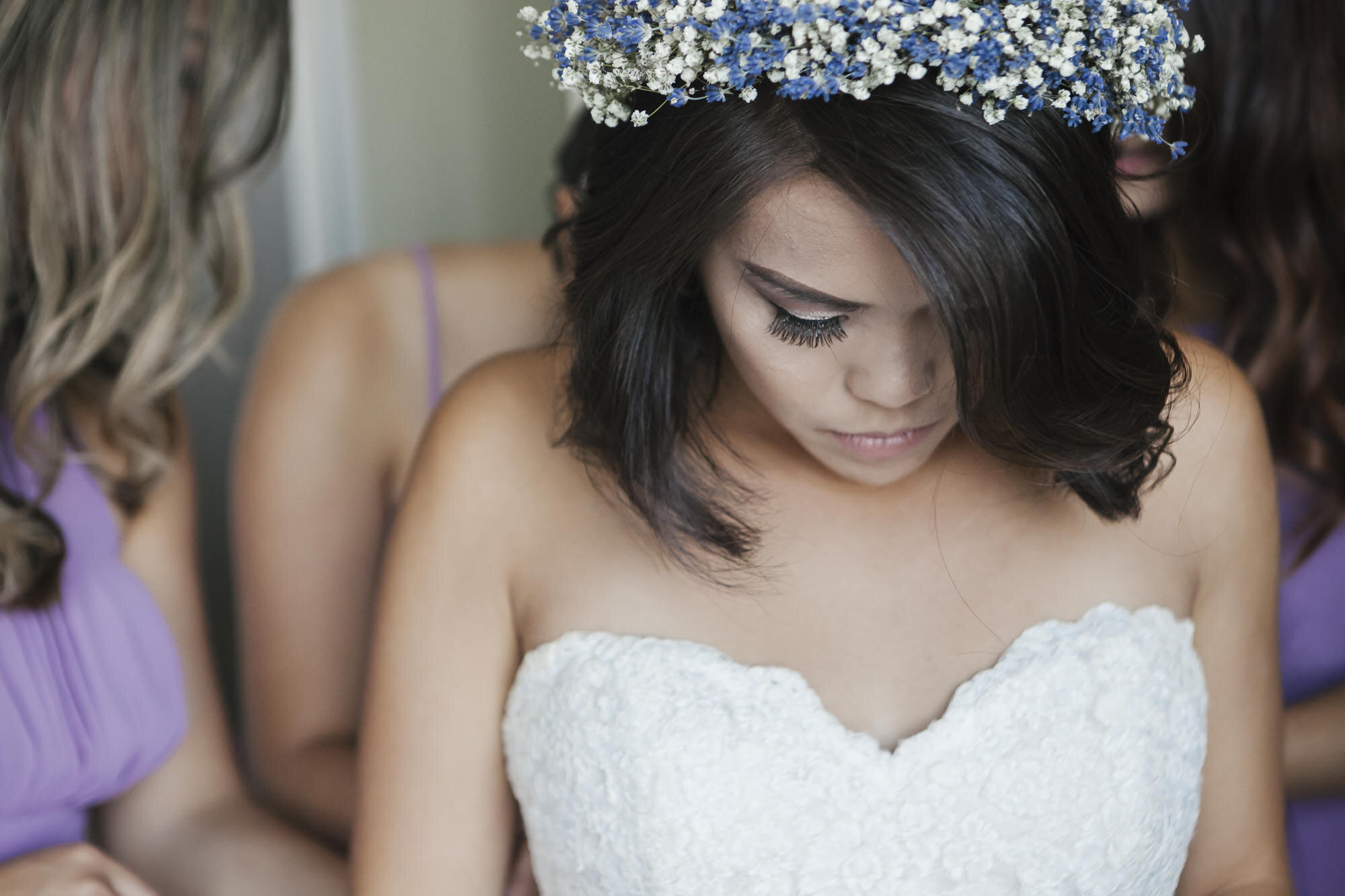 Bridesmaids in purple help bride in flower crown get dressed