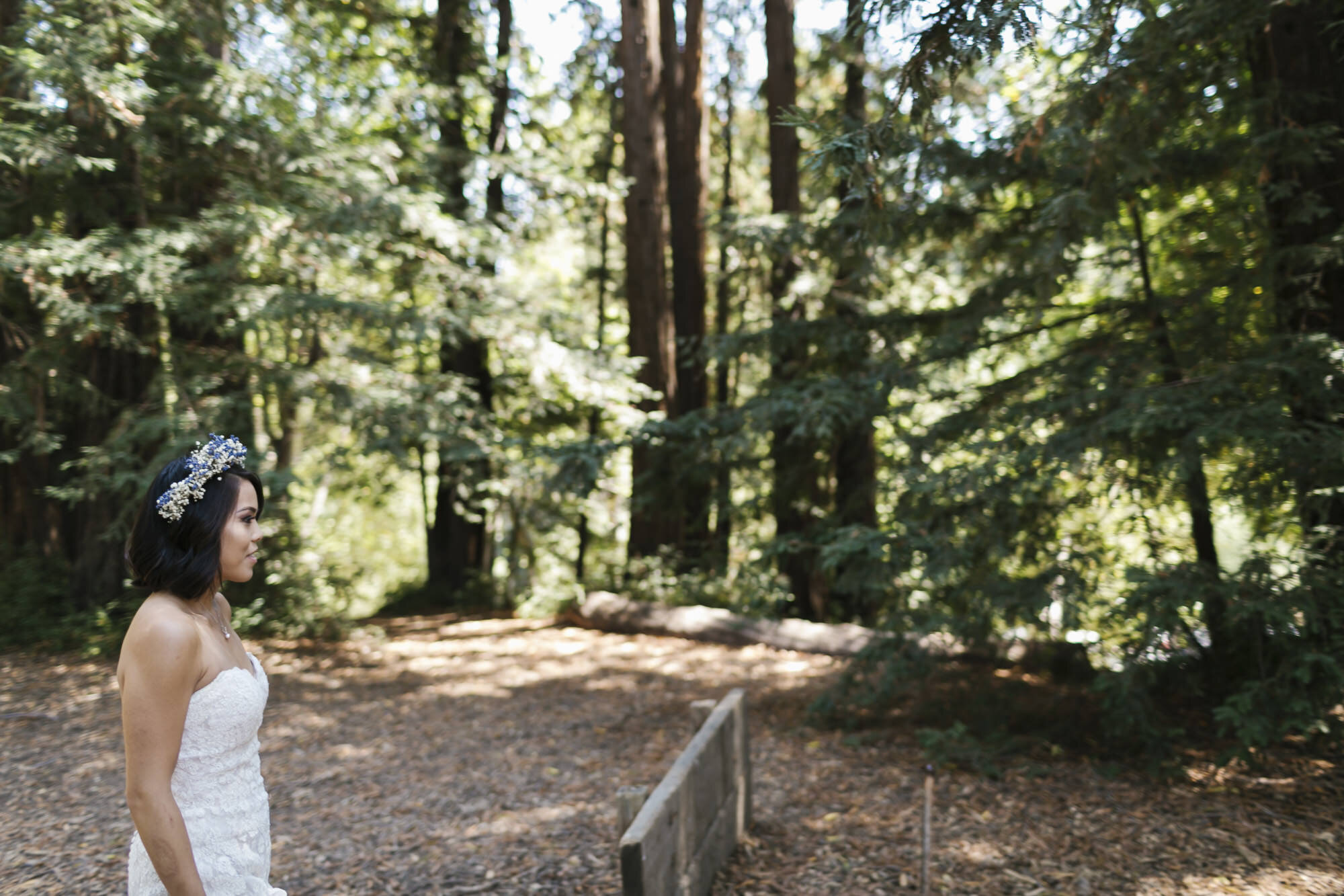Bride with flower crown approaches her groom in redwood forest