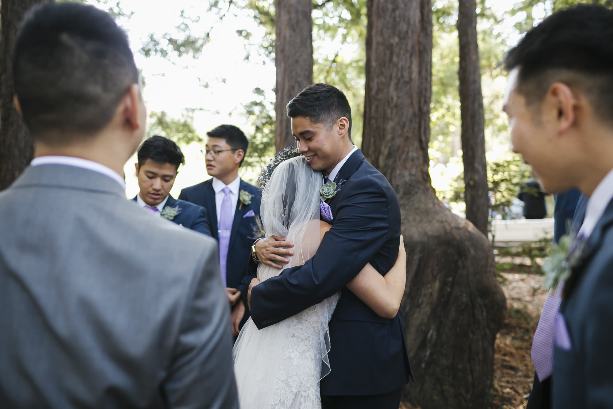 Wedding party hugs bride and groom after ceremony