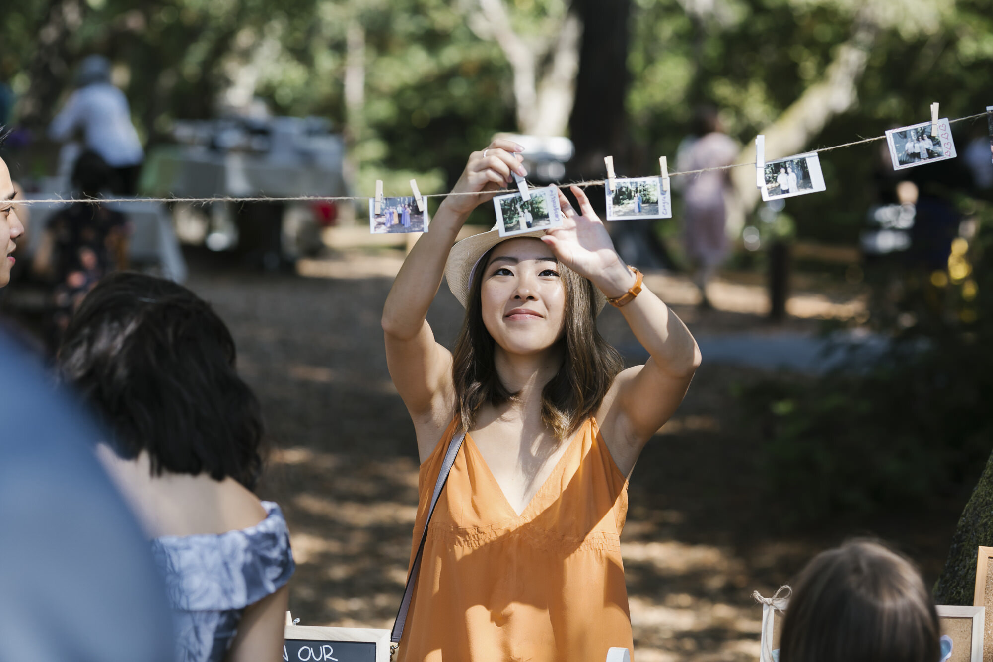 Wedding guest hangs polaroid photo up at cocktail reception