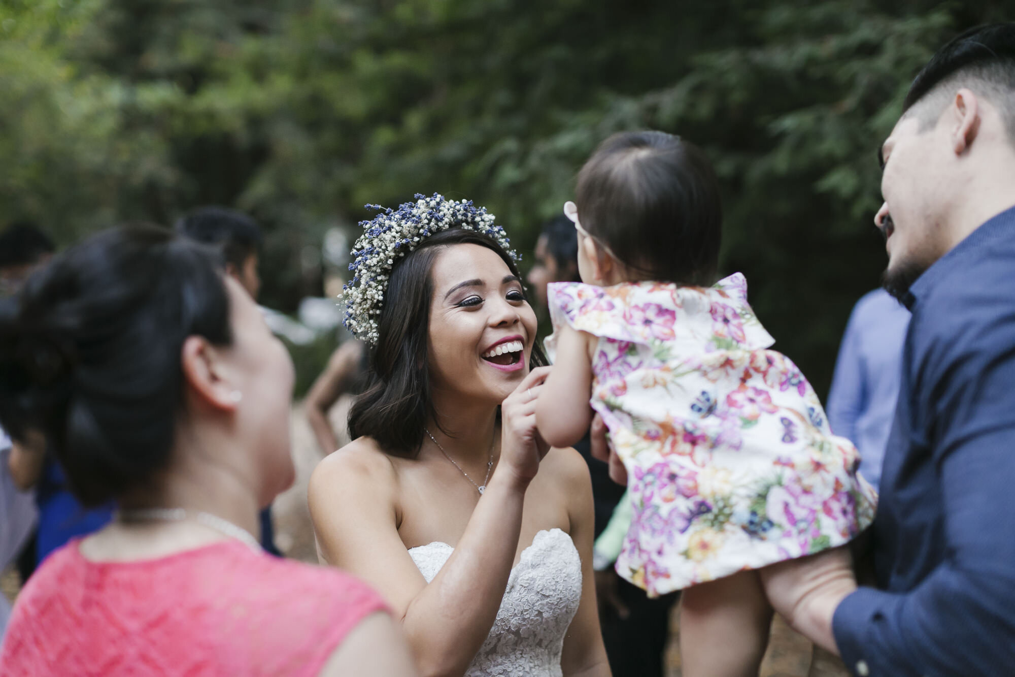 Bride dances with baby during outdoor wedding reception in a redwood forest