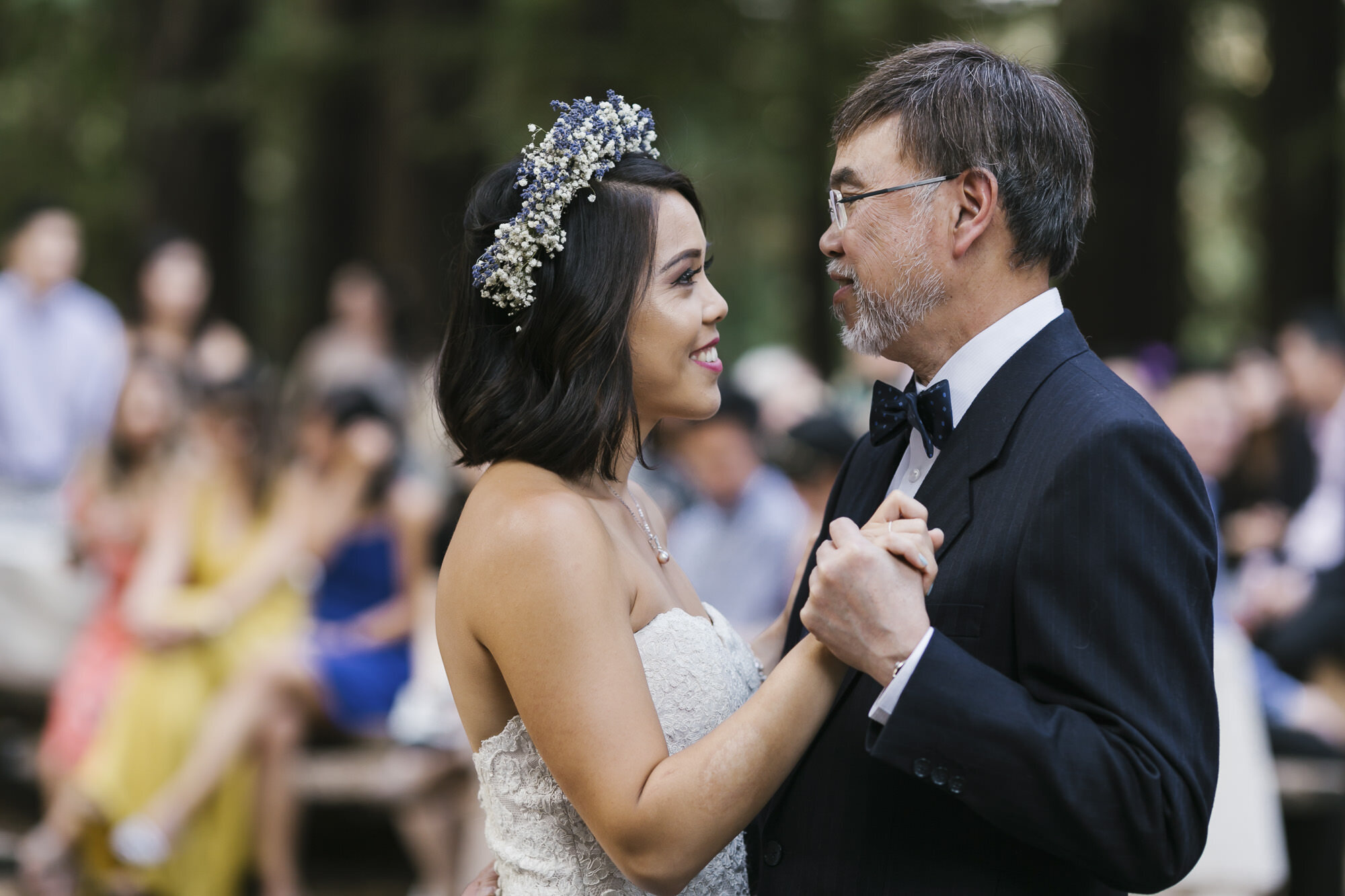 Bride dances with her father in a redwood grove