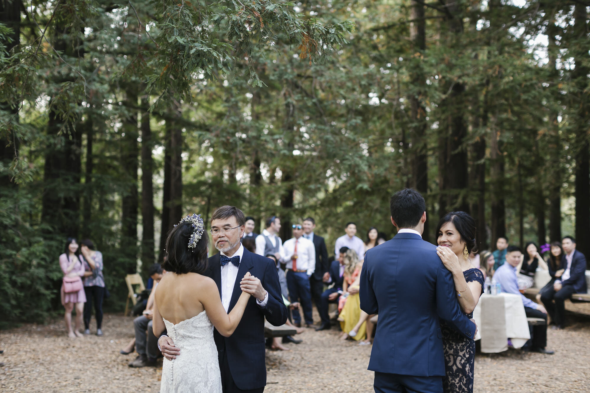 Bride and groom dance with their parents in a redwood grove