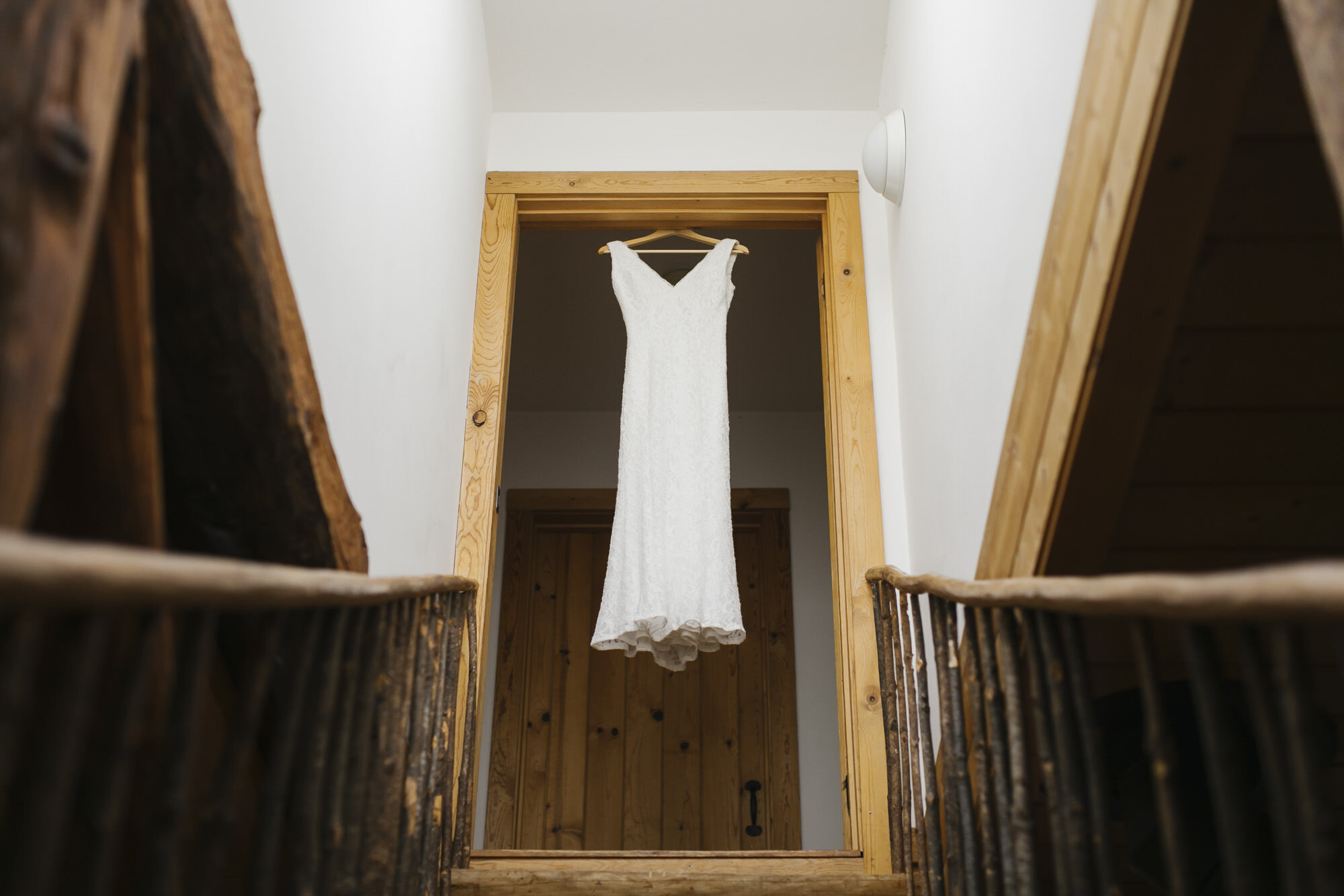 Wedding dress hangs in doorway of wood cabin