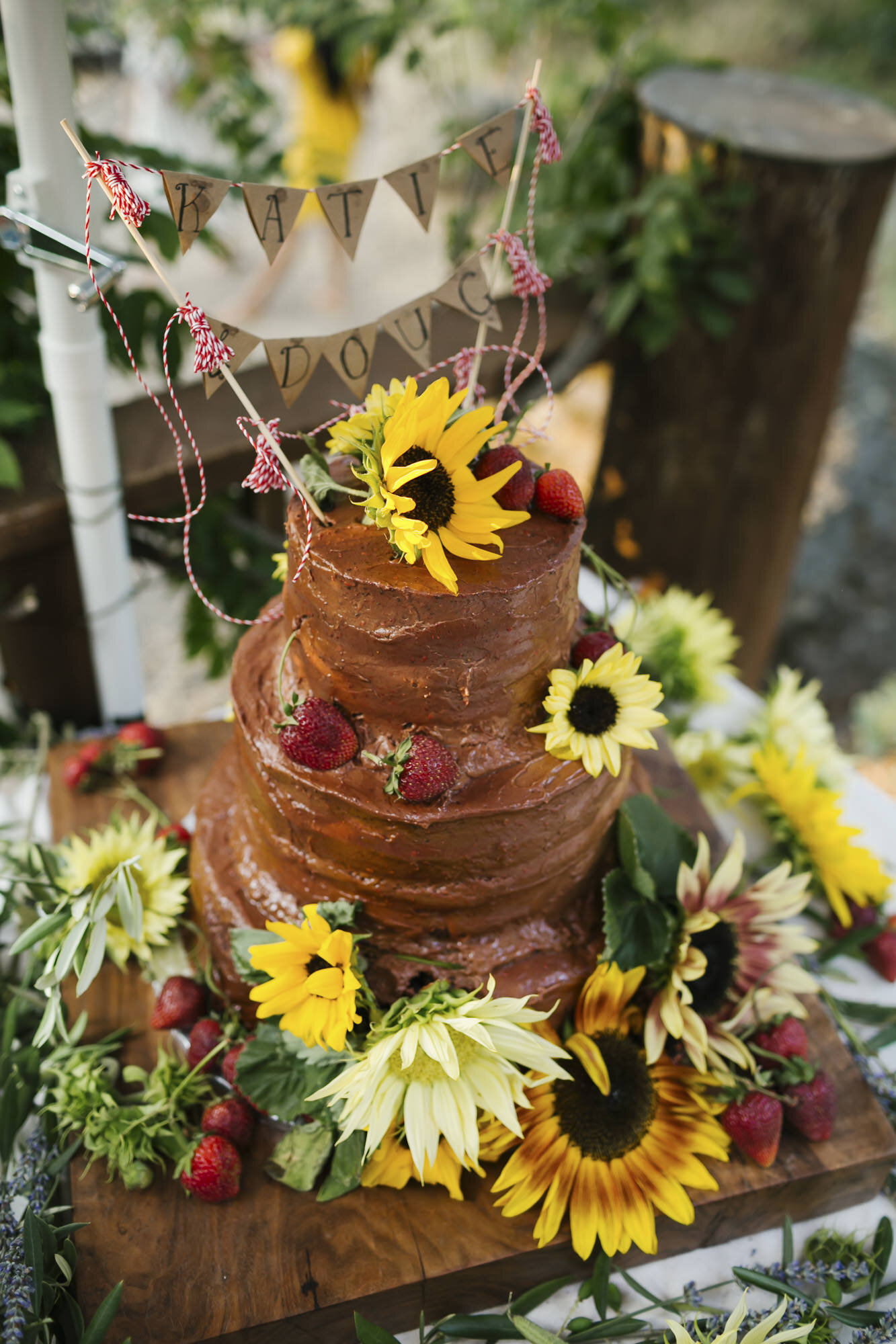 Chocolate wedding cake covered in sunflowers and pennant flag banner