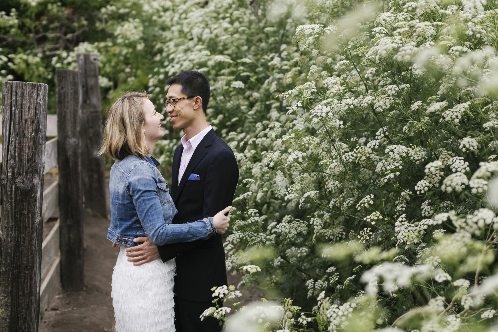 Married couple hug next to white wildflowers