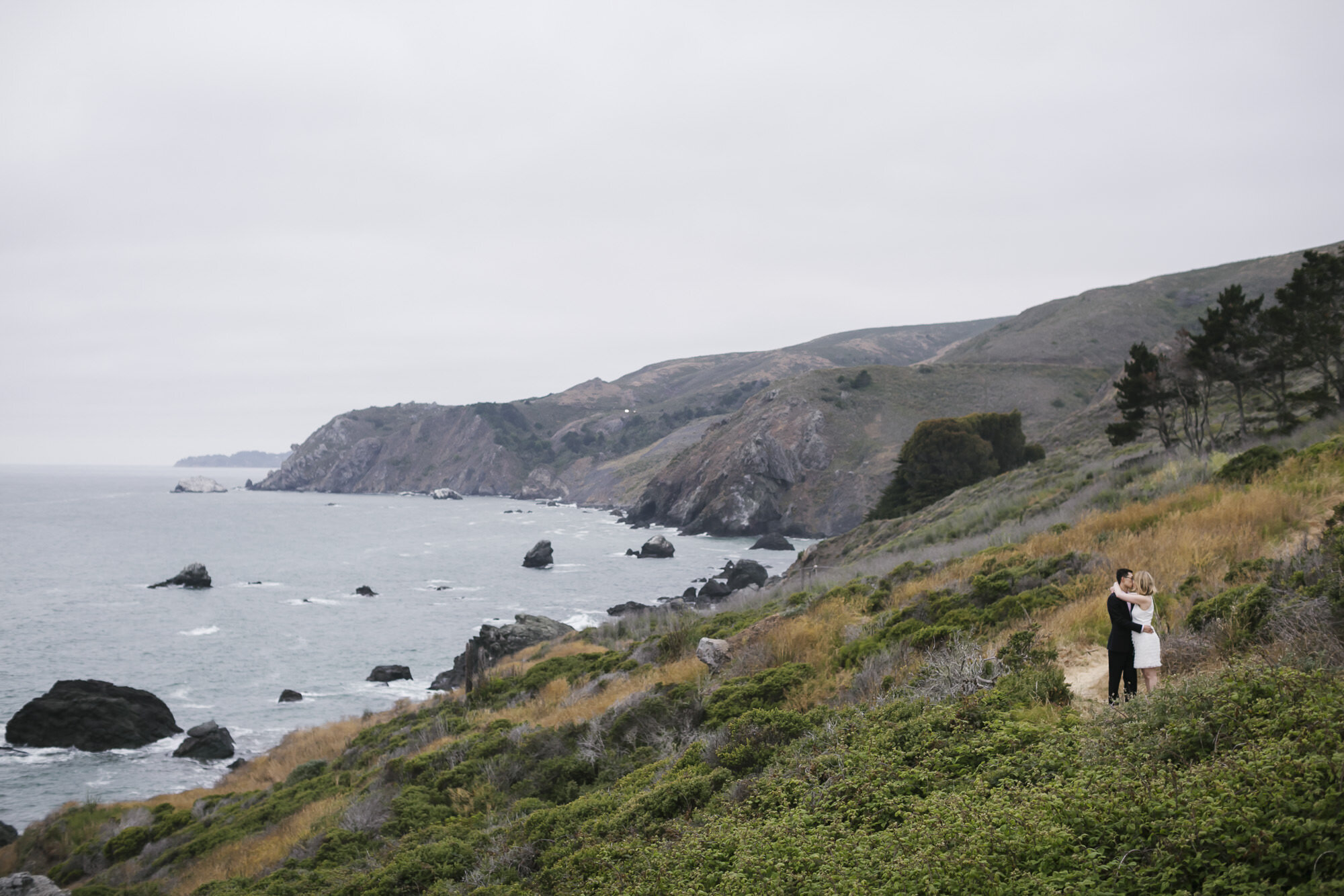 Wedding couple kiss on hiking trail with coastal view