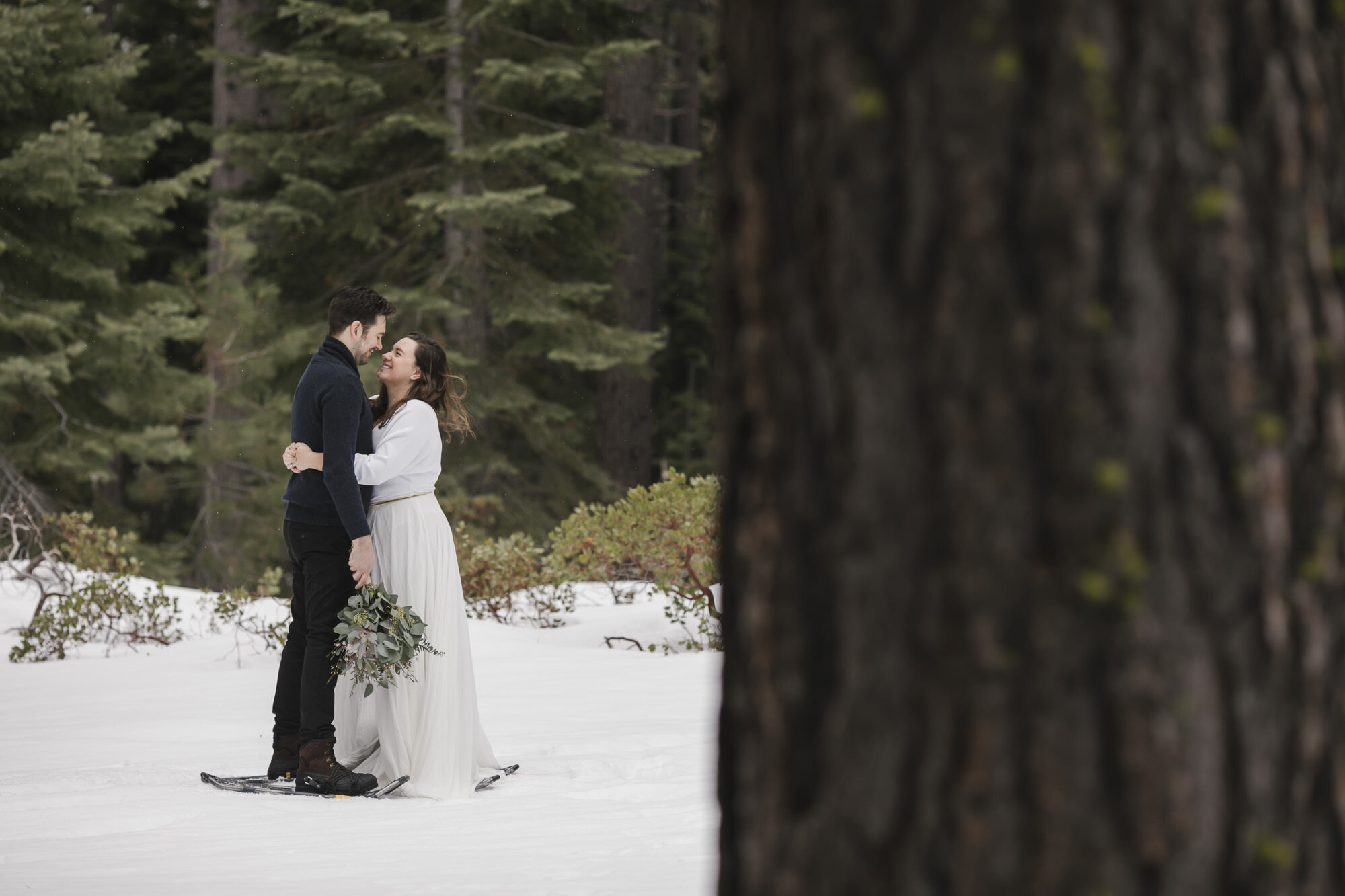Bride and groom hug in a snowy forest during their elopement in Lake Tahoe
