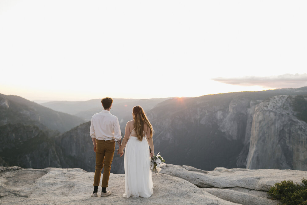 Bride and groom hold hands looking out at the view at Taft Point during their elopement in Yosemite National Park