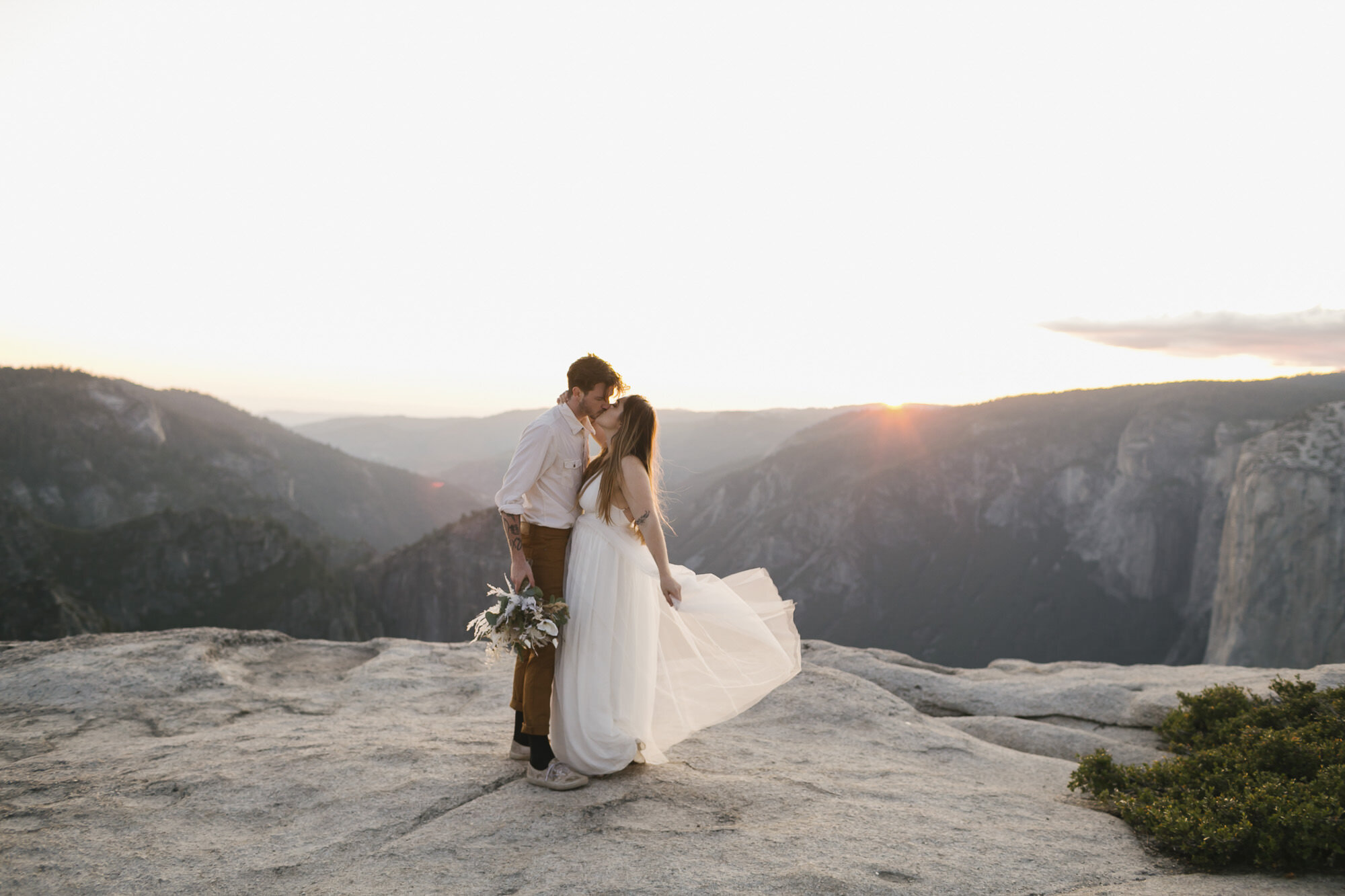 Wedding couple kiss at Taft Point during their adventure elopement in Yosemite at sunset
