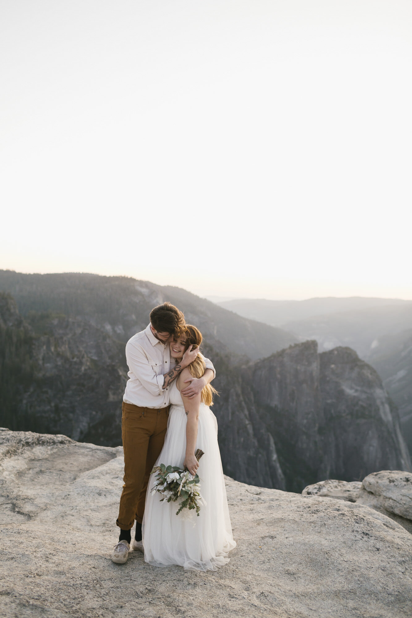 Wedding couple cuddle at Taft Point during their adventure elopement in Yosemite