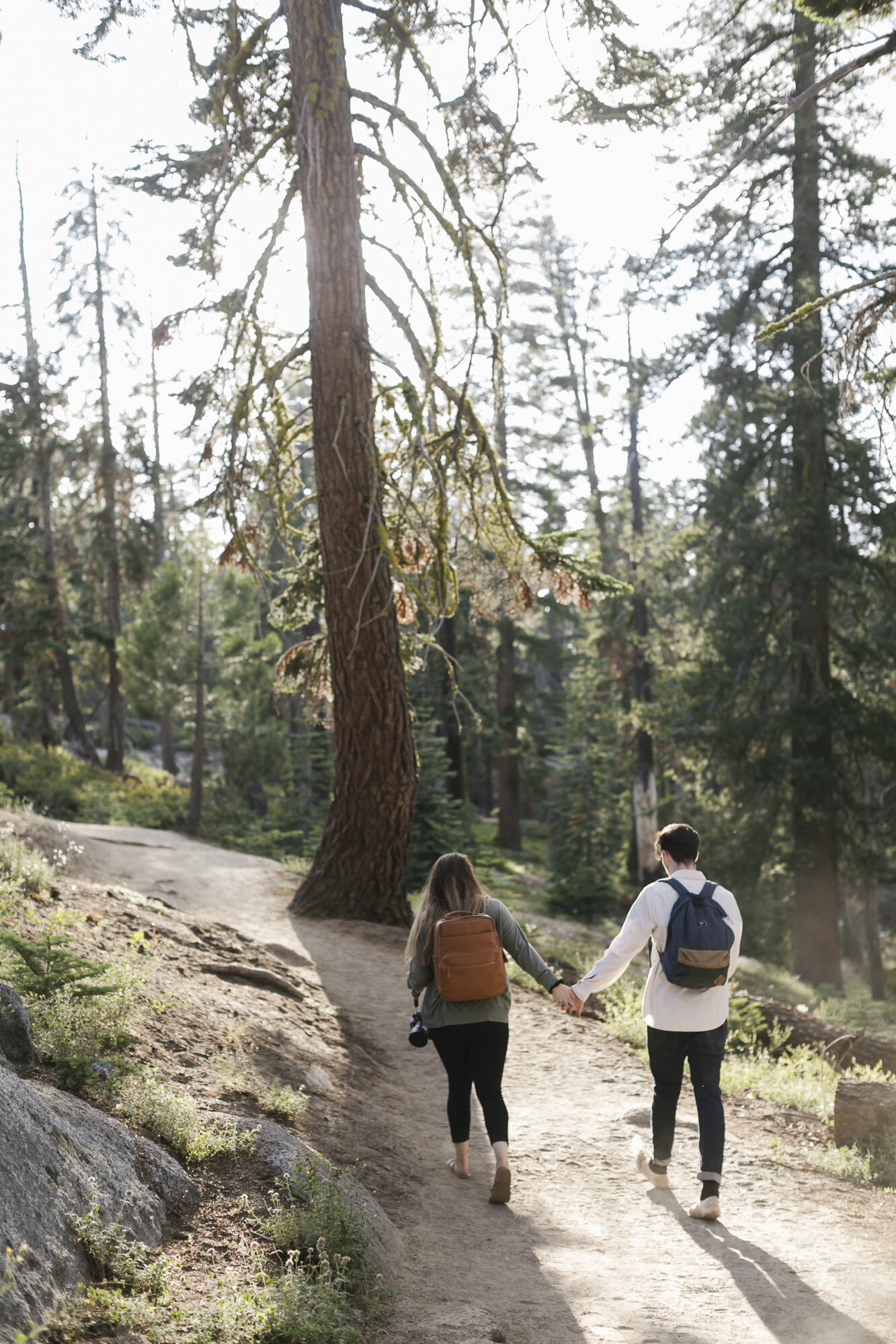 Couple hike together holding hands in Yosemite National Park on their way to Taft Point for their elopement