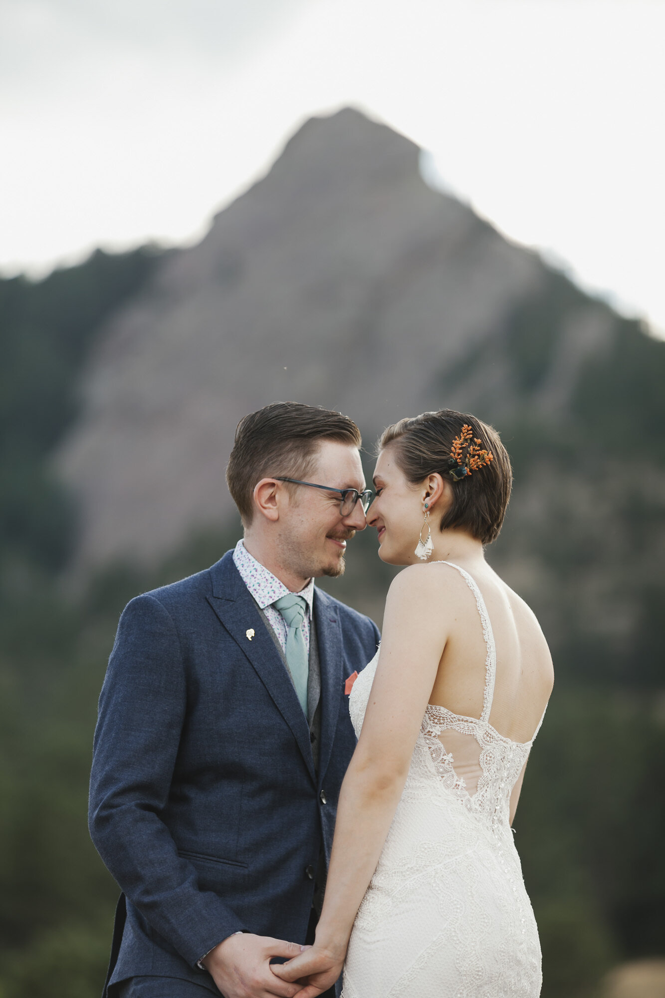 Wedding couple snuggle close in front of the Flatirons in Colorado