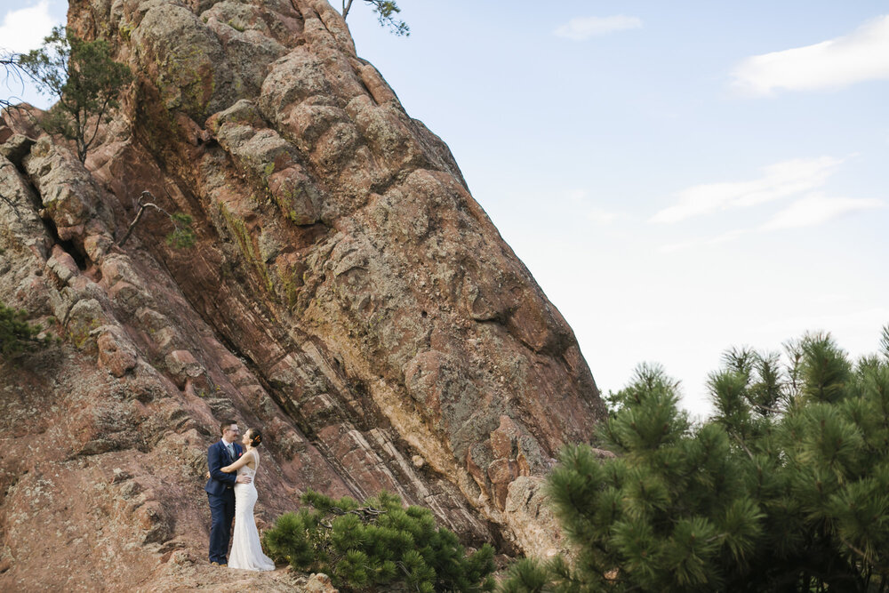 Just married couple stand in front of massive red rock formation in Colorado