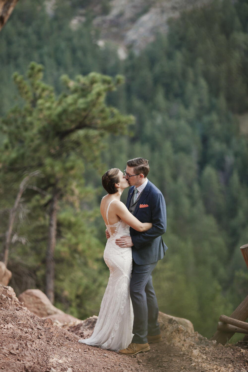 Adventure elopement couple kiss with a forest of trees behind them near Boulder Colorado