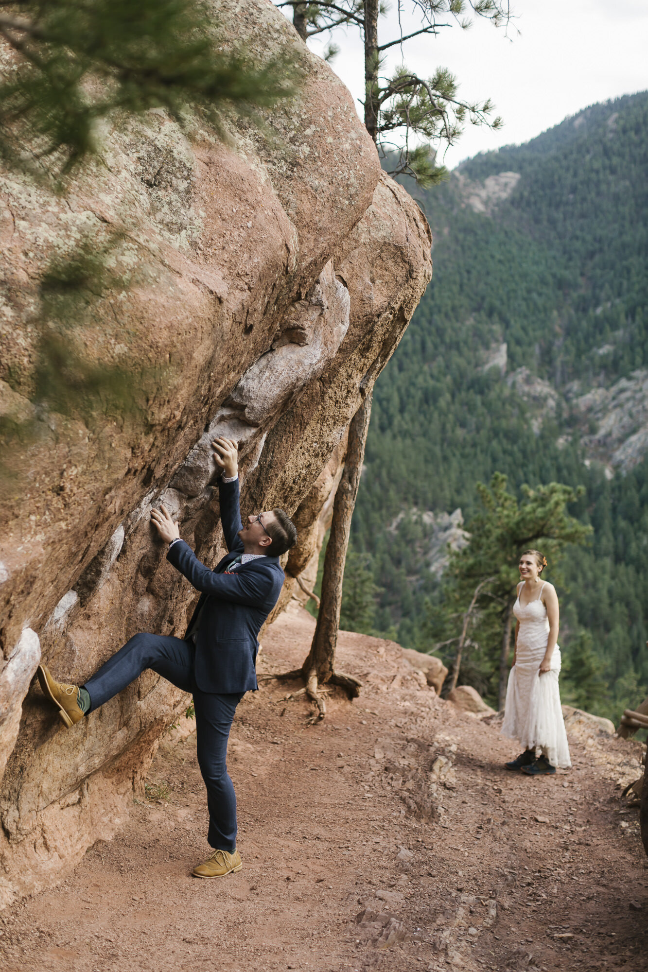 Groom playfully rock climbing on his wedding day near Boulder Colorado