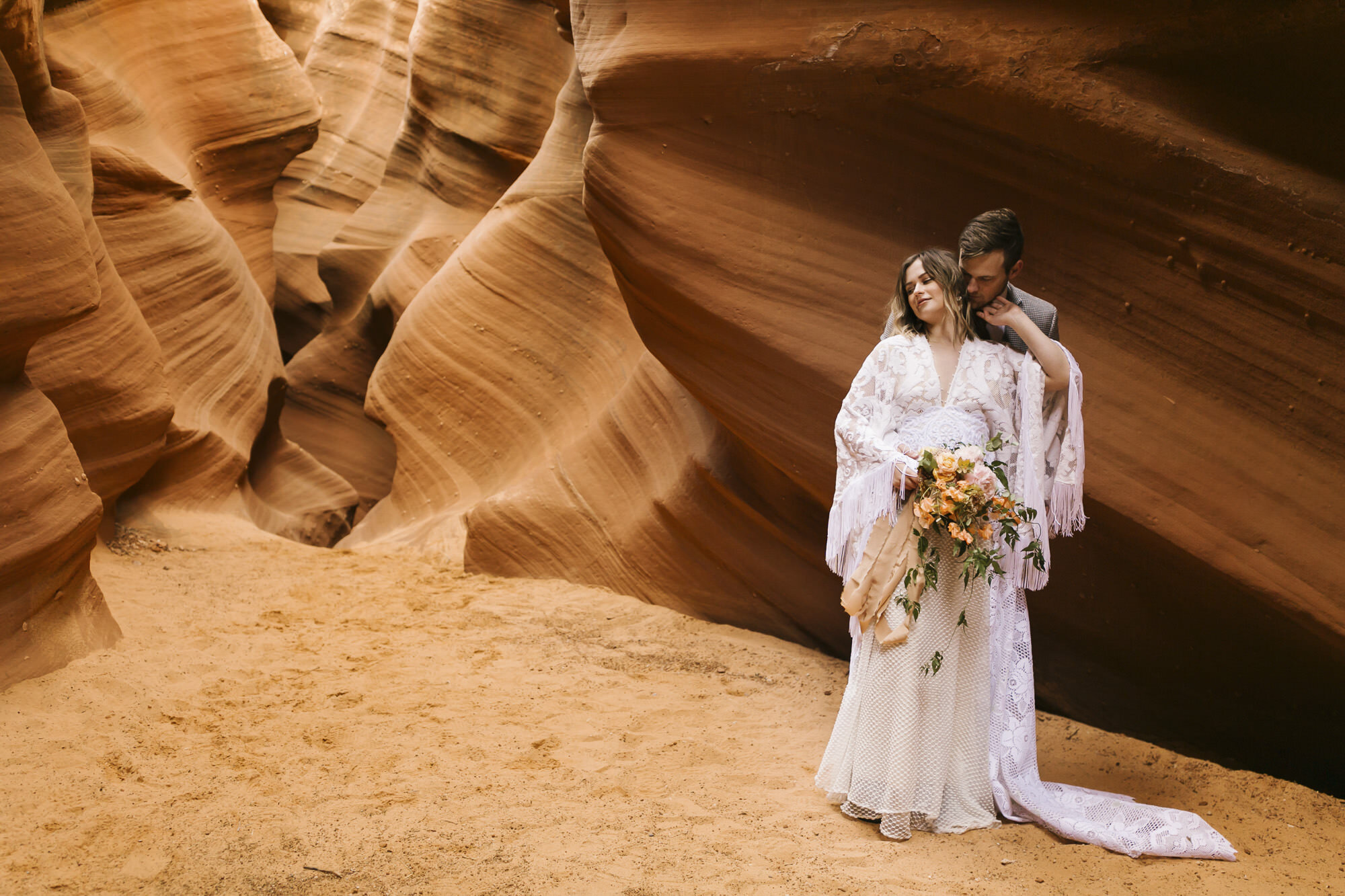 Just married couple stand together in slot canyon