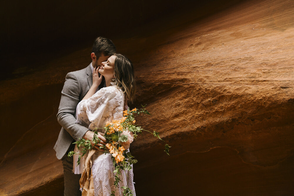 Wedding couple snuggle in dramatic light in an Arizona slot canyon