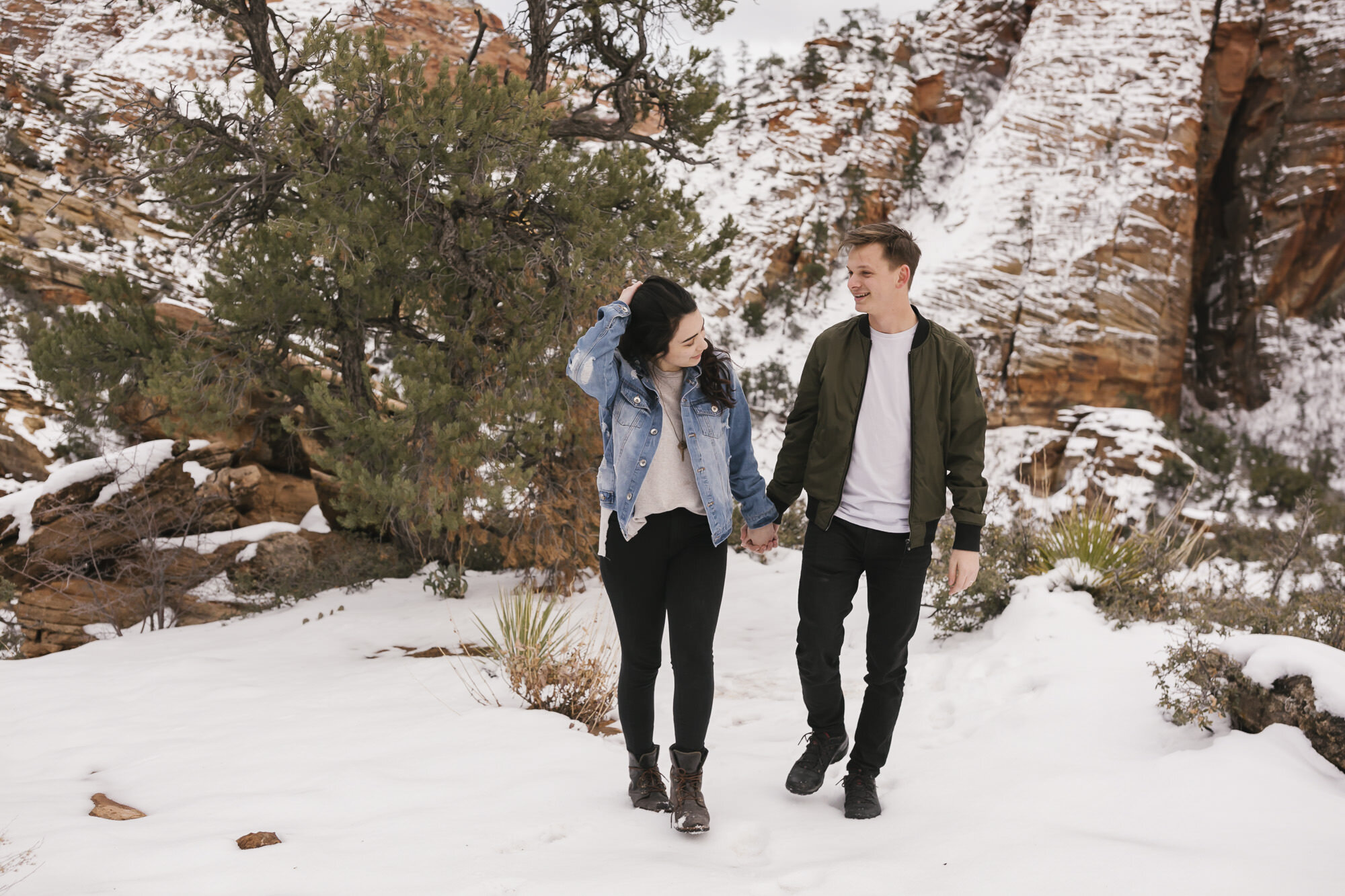 Couple walk through the snow in Zion for their engagement photos